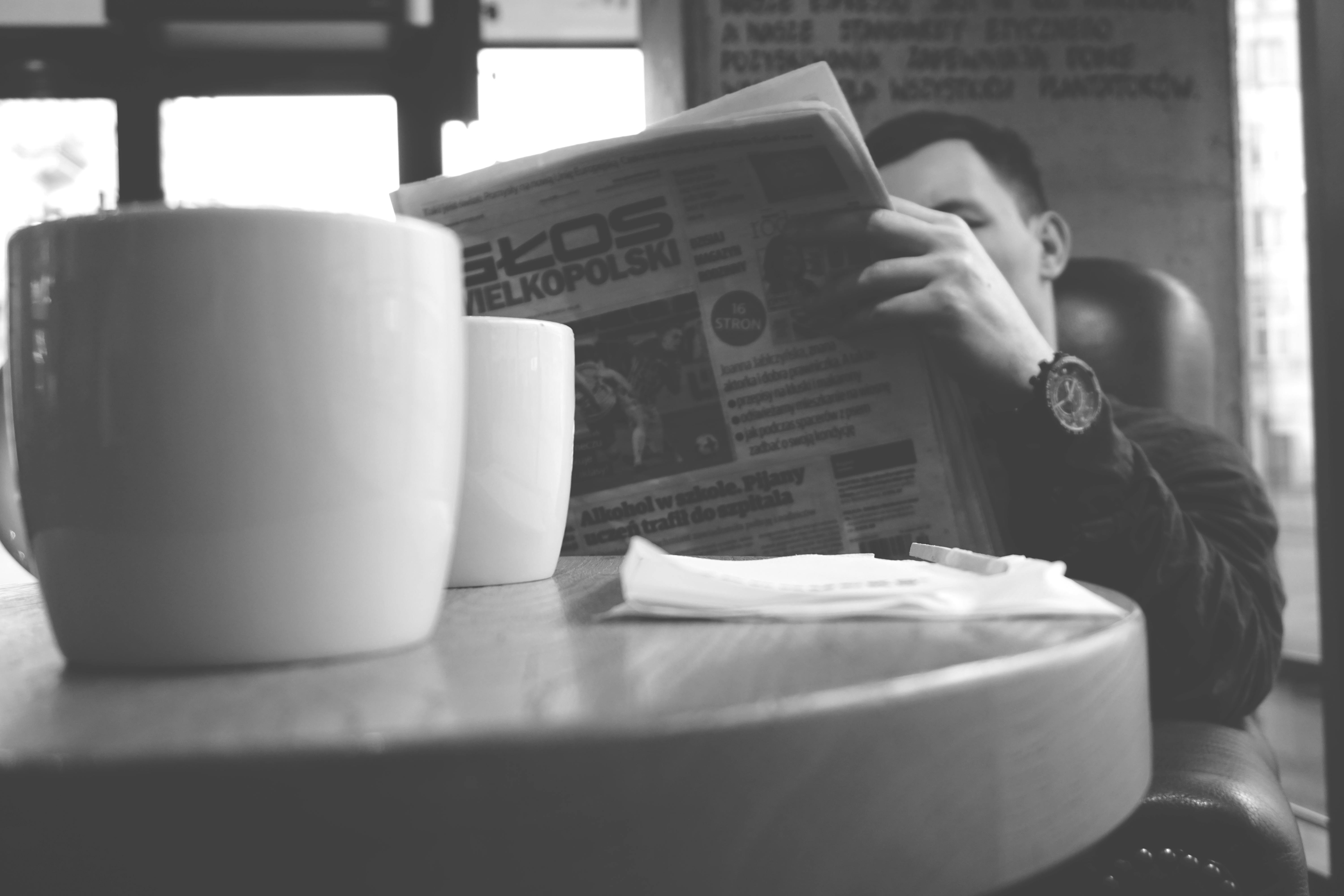 A man reading a newspaper at a table | Source: Pexels