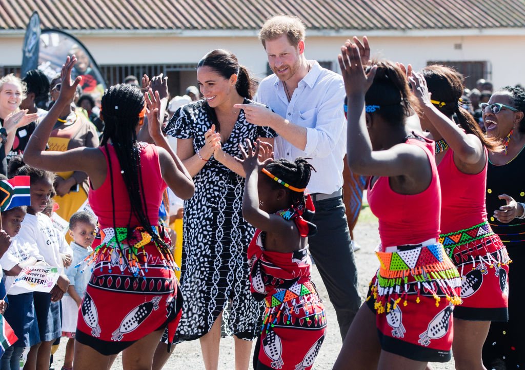 Prince Harry, Duke of Sussex and Meghan, Duchess of Sussex dance as they arrive for a visit to the "Justice desk", an NGO in the township of Nyanga in Cape Town, as they begin their tour of the region on September 23, 2019. | Source: Getty Images
