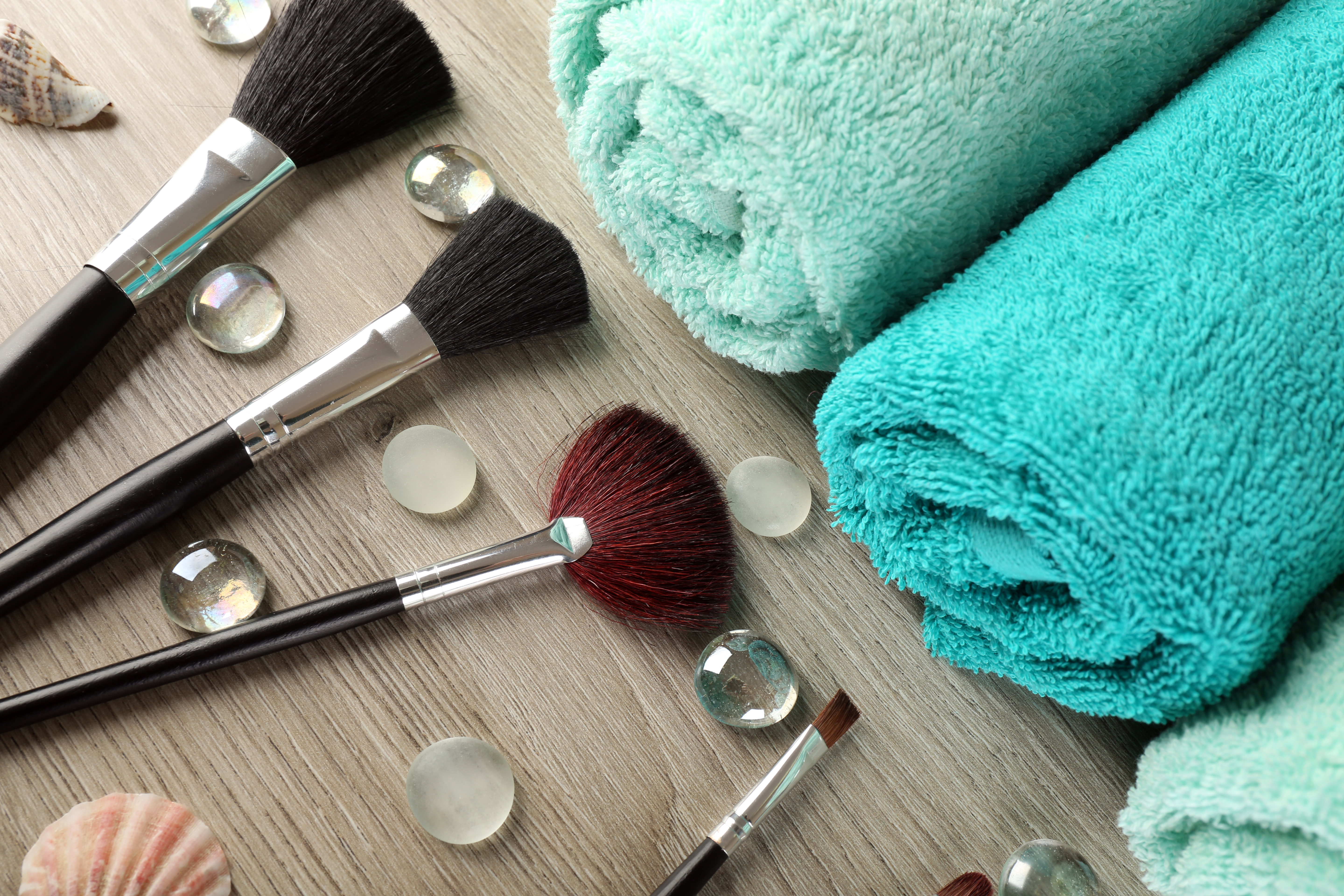 Makeup brushes spread across a counter opposite a row of rolled towels | Source: Shutterstock