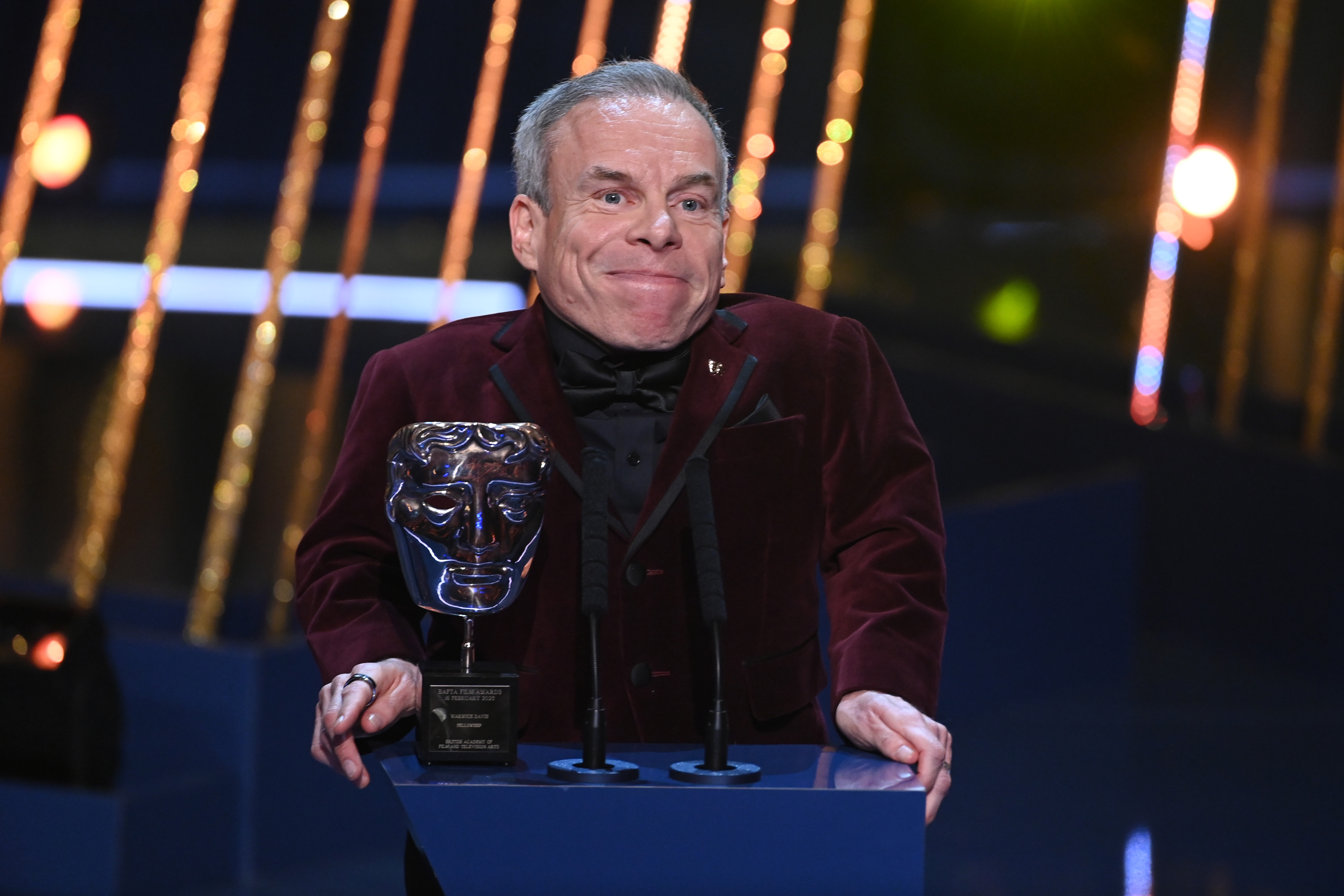 Warwick Davis accepts his Fellowship Award on stage on February 16, 2025 | Source: Getty Images