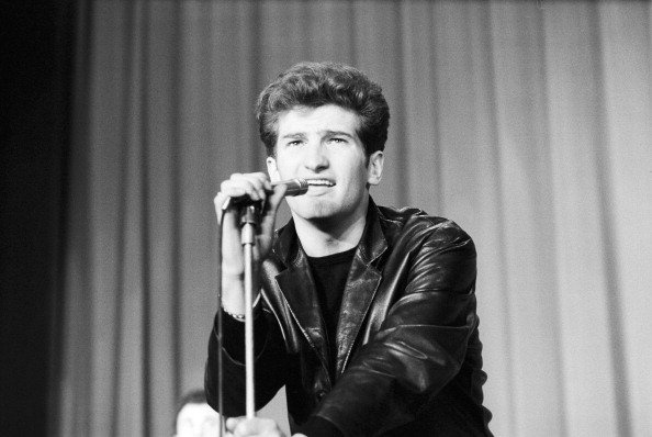 Claude MOINE alias Eddy MITCHELL chantant au micro sur scène . |Photo : Getty Images