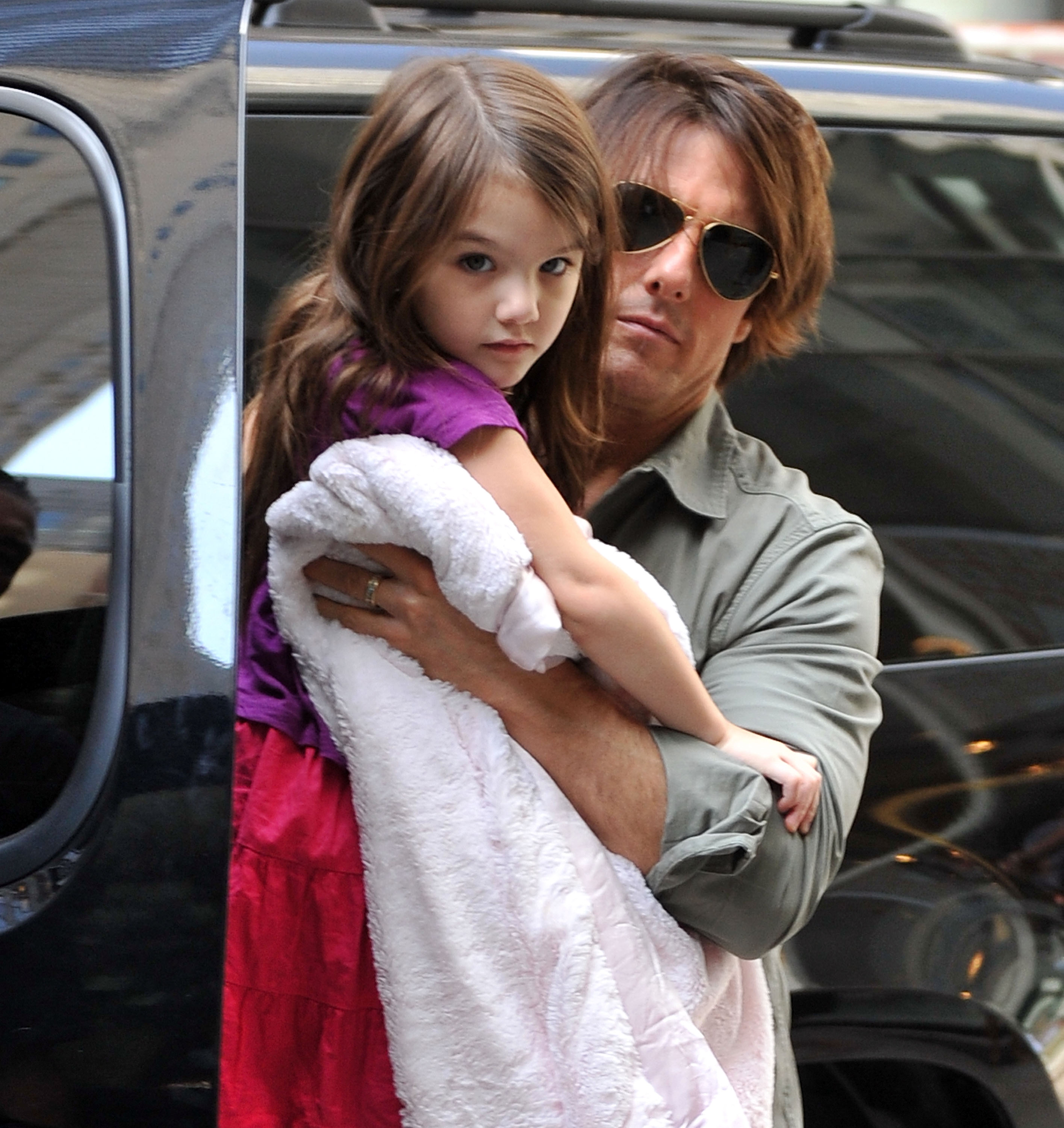 Tom Cruise carries Suri Cruise outside FAO Schwarz during a visit to the iconic toy store in New York City. | Source: Getty Images