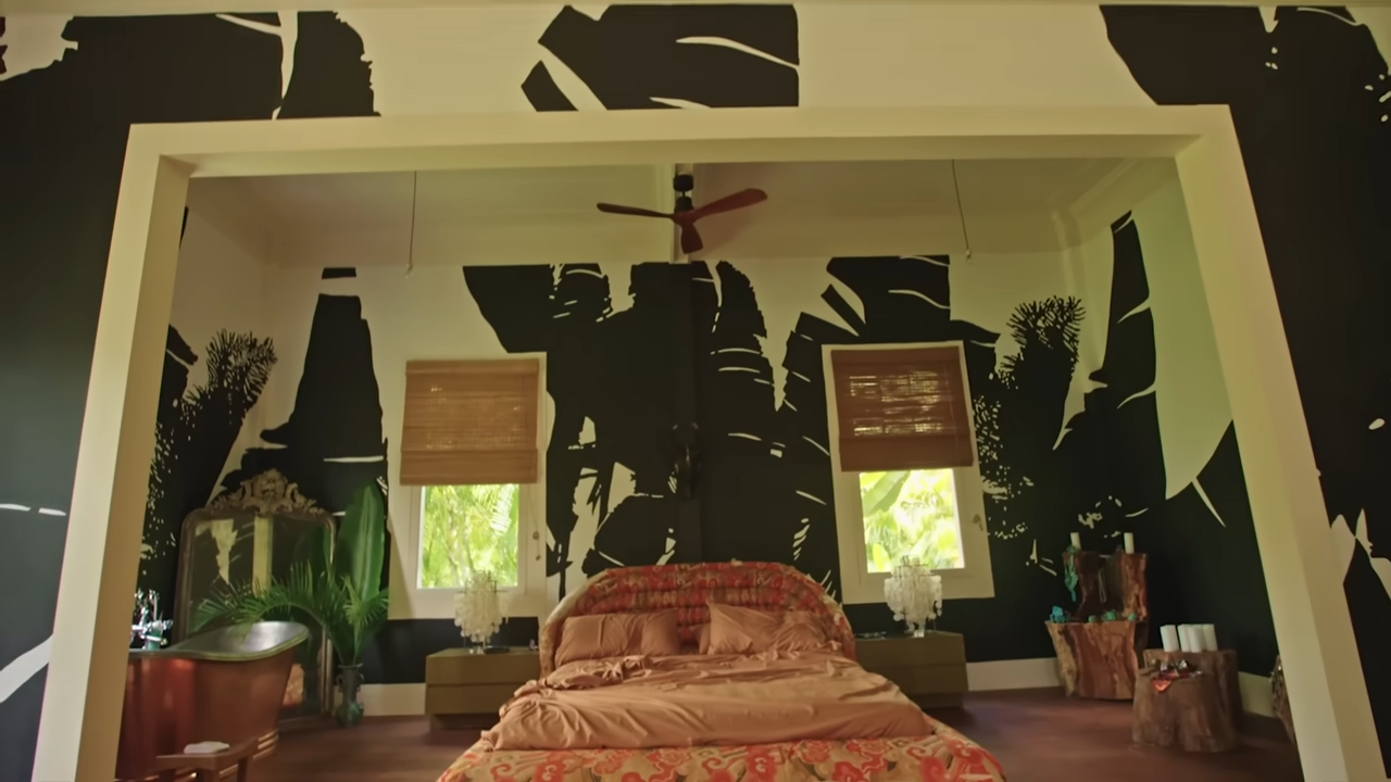 The master bedroom loft showcases a custom copper bathtub, a rustic bed, and graphic, hand-painted banana leaf murals. | Source: YouTube/@Archdigest