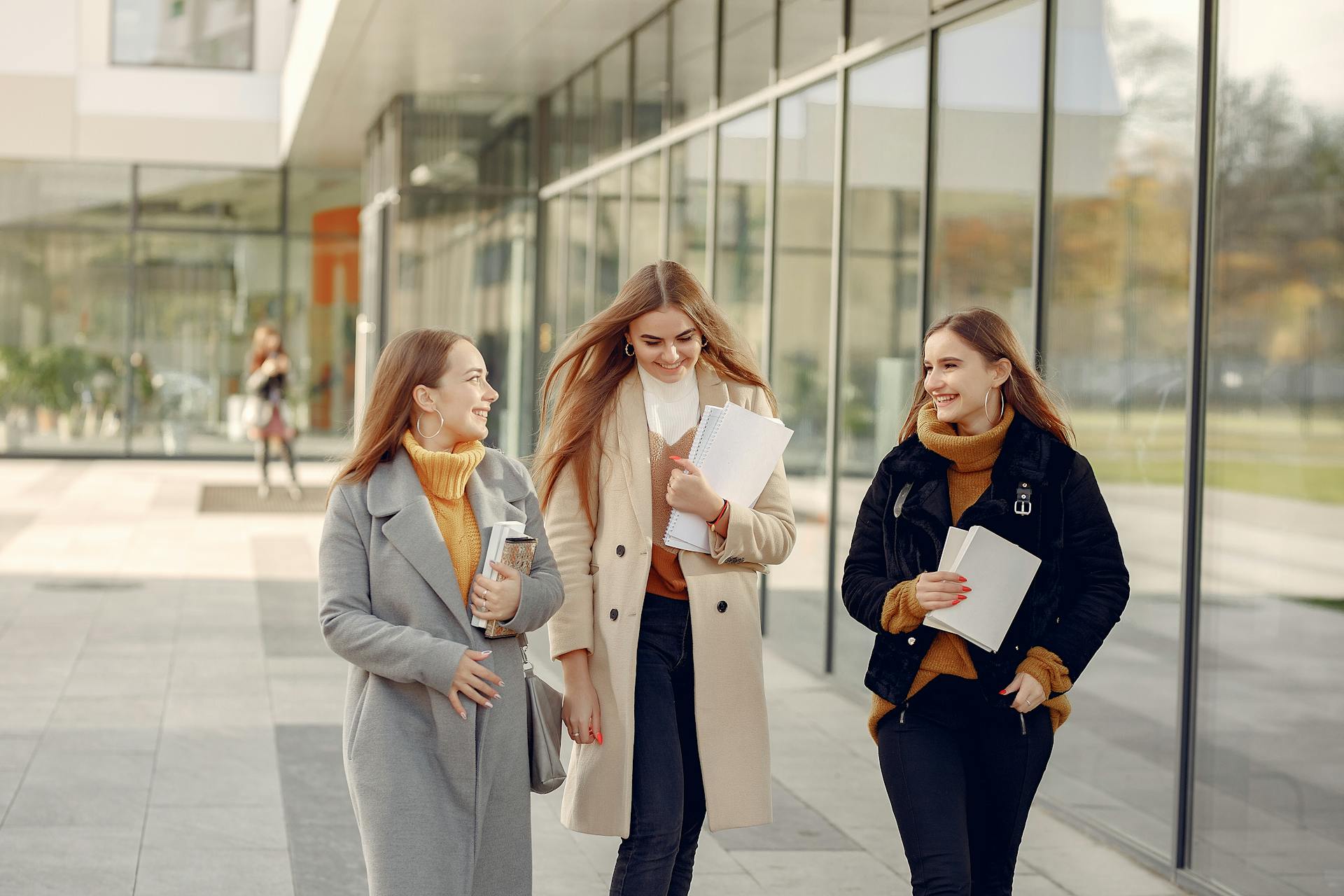 Three female students smiling while discussing their day in college | Source: Pexels