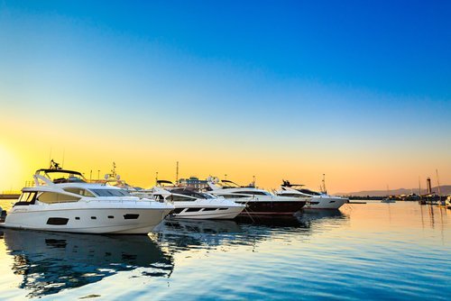 Luxury yachts docked at sea port at sunset. | Source: Shutterstock.