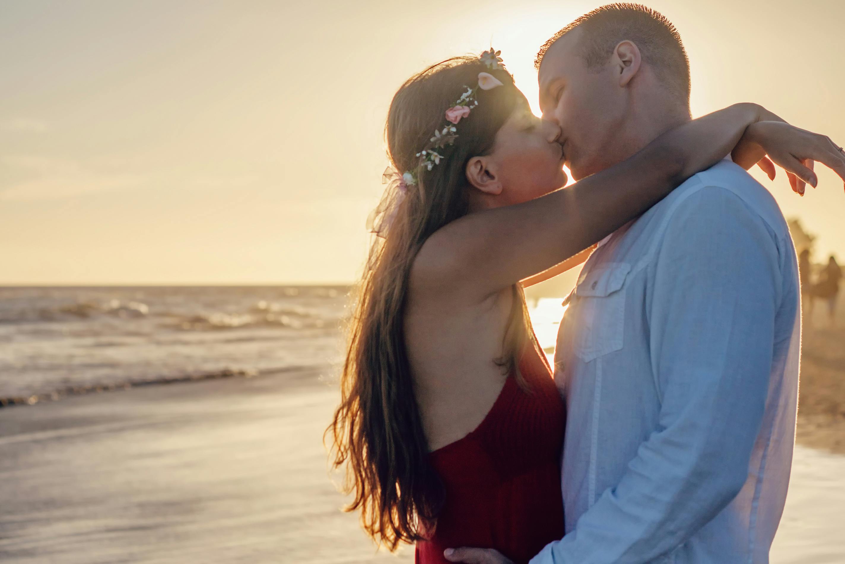 A loved-up couple kissing in front of a sunset at the beach | Source: Pexels