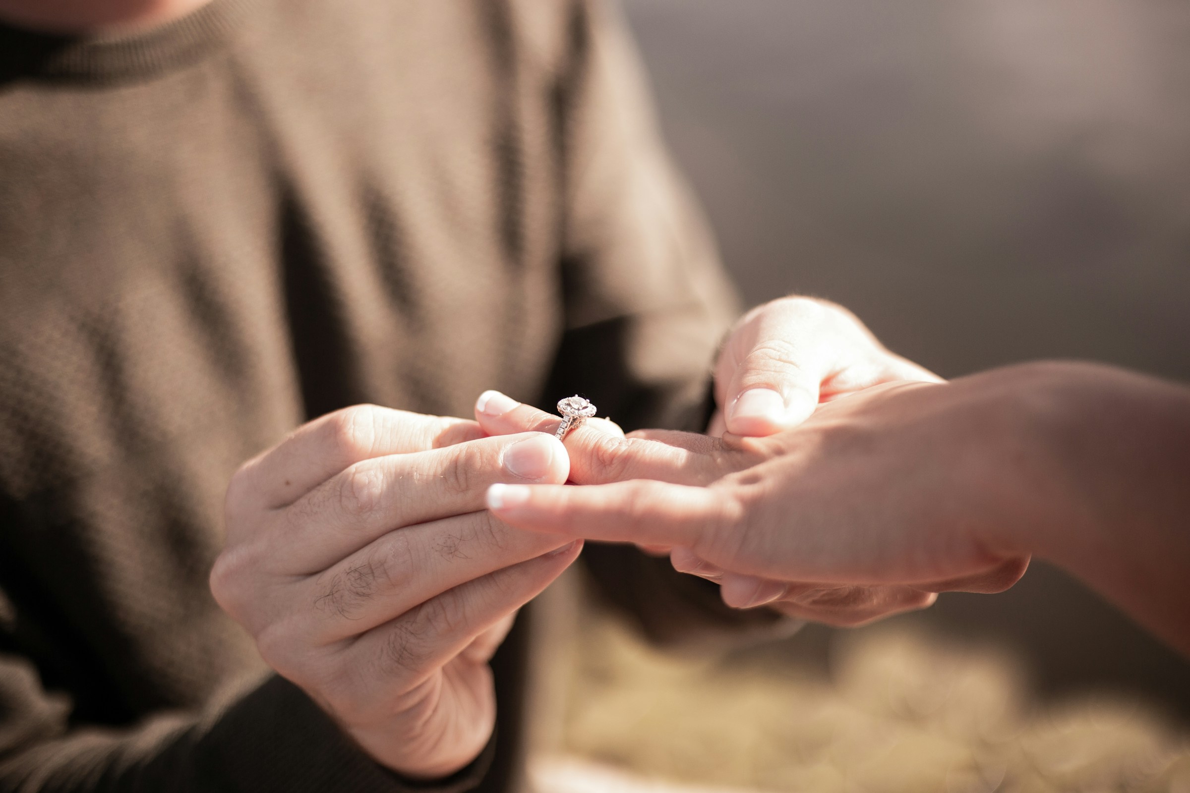 A close-up shot of a man slipping a ring on his girlfriend's finger | Source: Unsplash