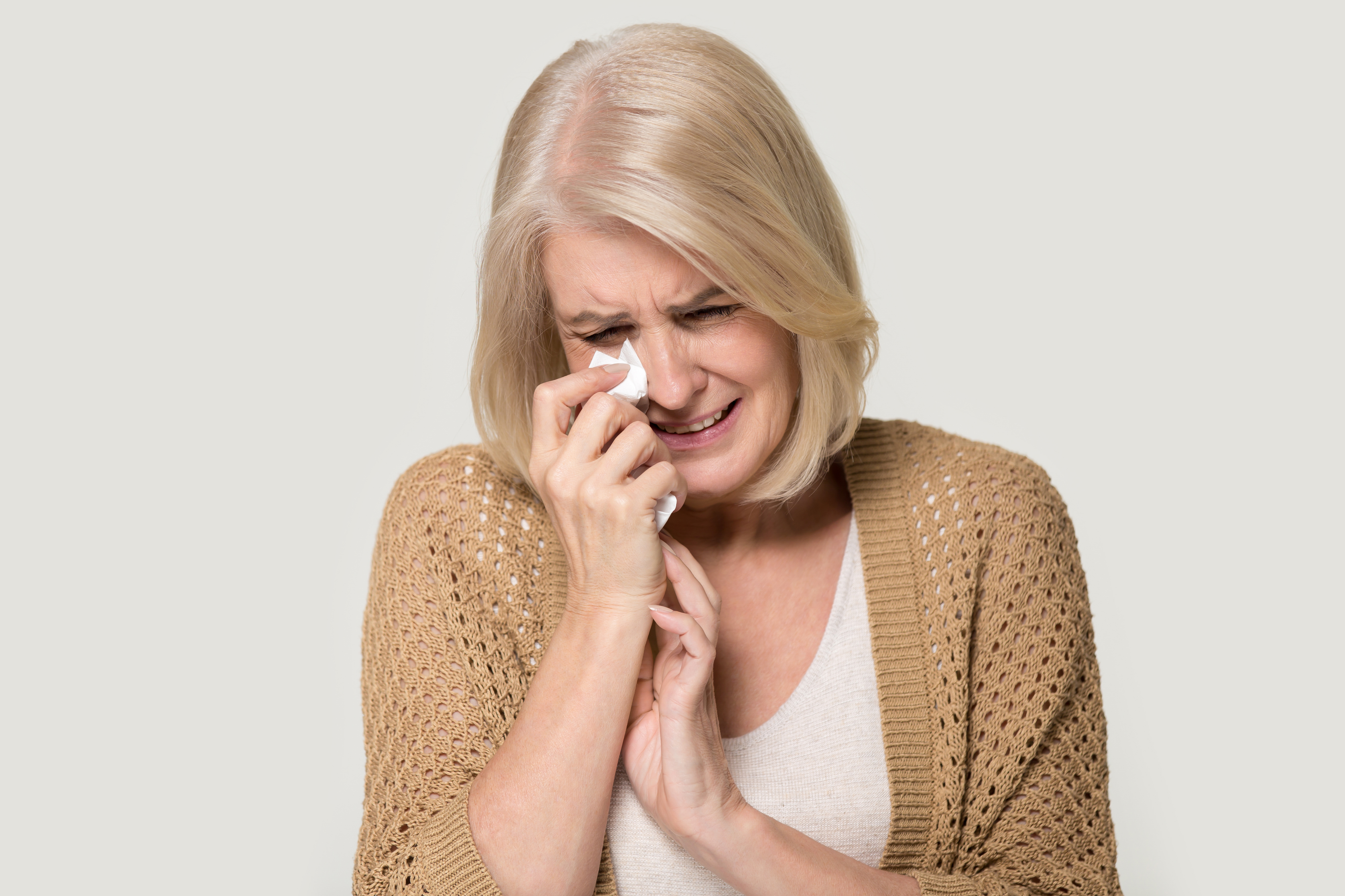A crying senior lady wiping tears with her handkerchief | Source: Shutterstock