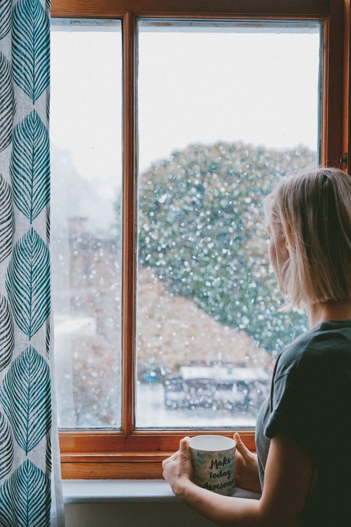 Una mujer joven mira por la ventana. | Foto: Unsplash