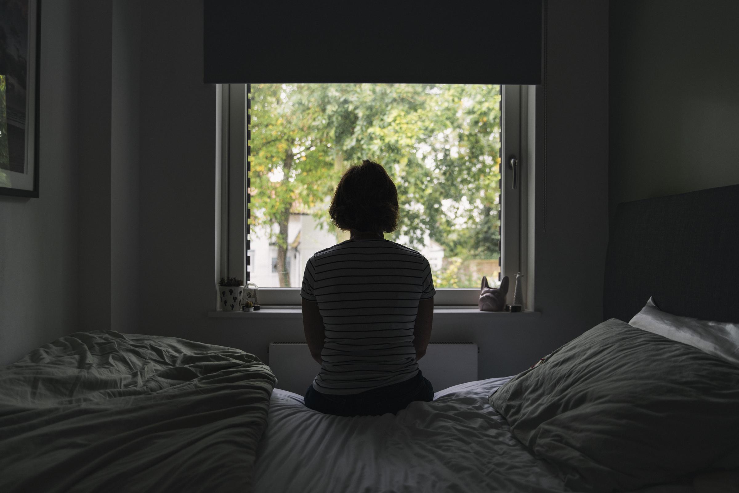 A woman staring out the window in her bedroom | Source: Getty Images