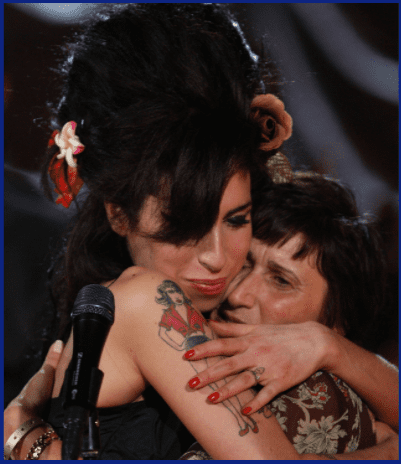 La chanteuse britannique Amy Winehouse (à gauche) embrasse sa mère Janis Winehouse après avoir accepté un Grammy Award aux Riverside Studios lors de la 50ème cérémonie des Grammy Awards par liaison vidéo, le 10 février 2008 à Londres, en Angleterre. | Photo : Getty Images