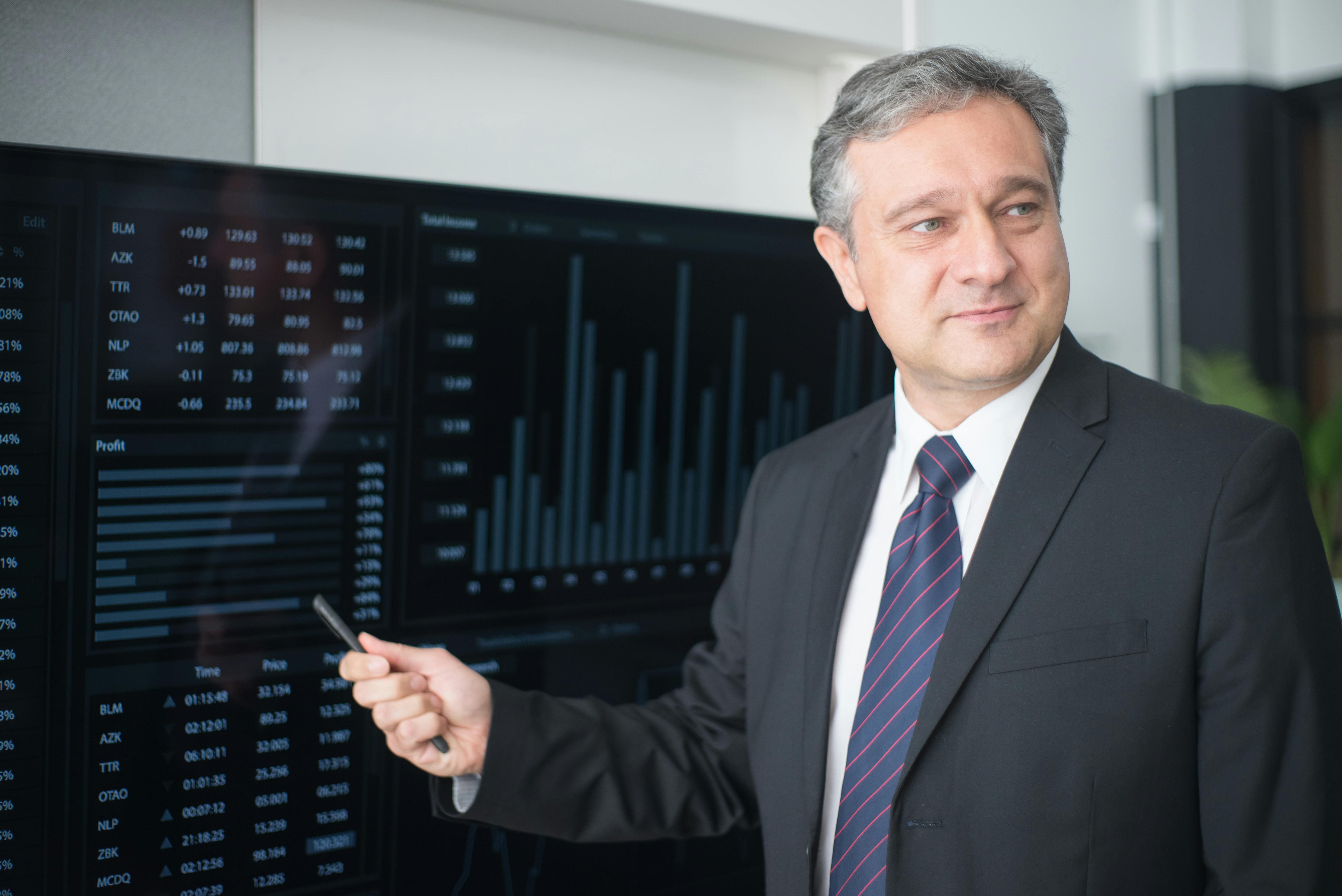 A man holding a pen and pointing at a monitor | Source: Pexels