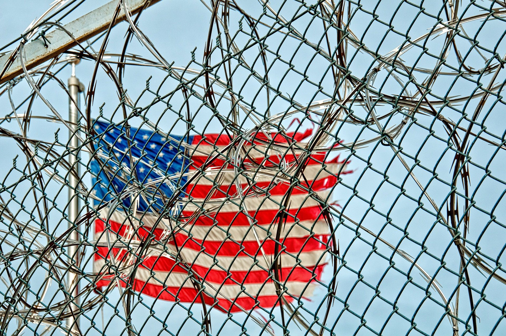 Pictured - Prison detention wire fence and the American flag | Source: Pixabay 