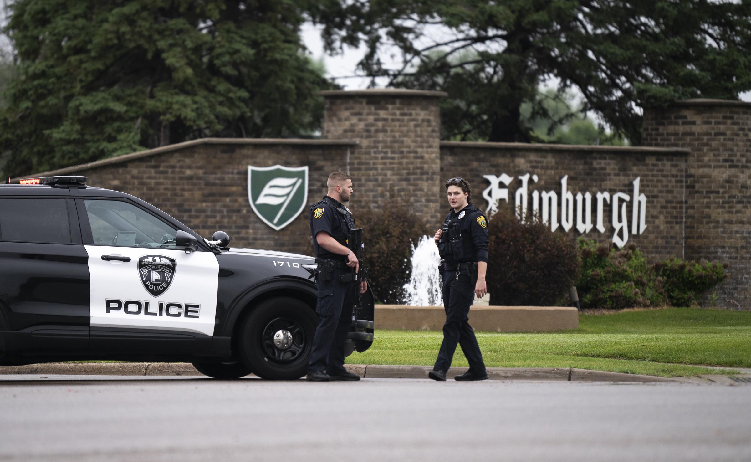 Brooklyn Park police officers speaks with each other as they guard the entrance to a neighborhood on June 14, 2025 in Brooklyn Park, Minnesota. | Source: Getty Images