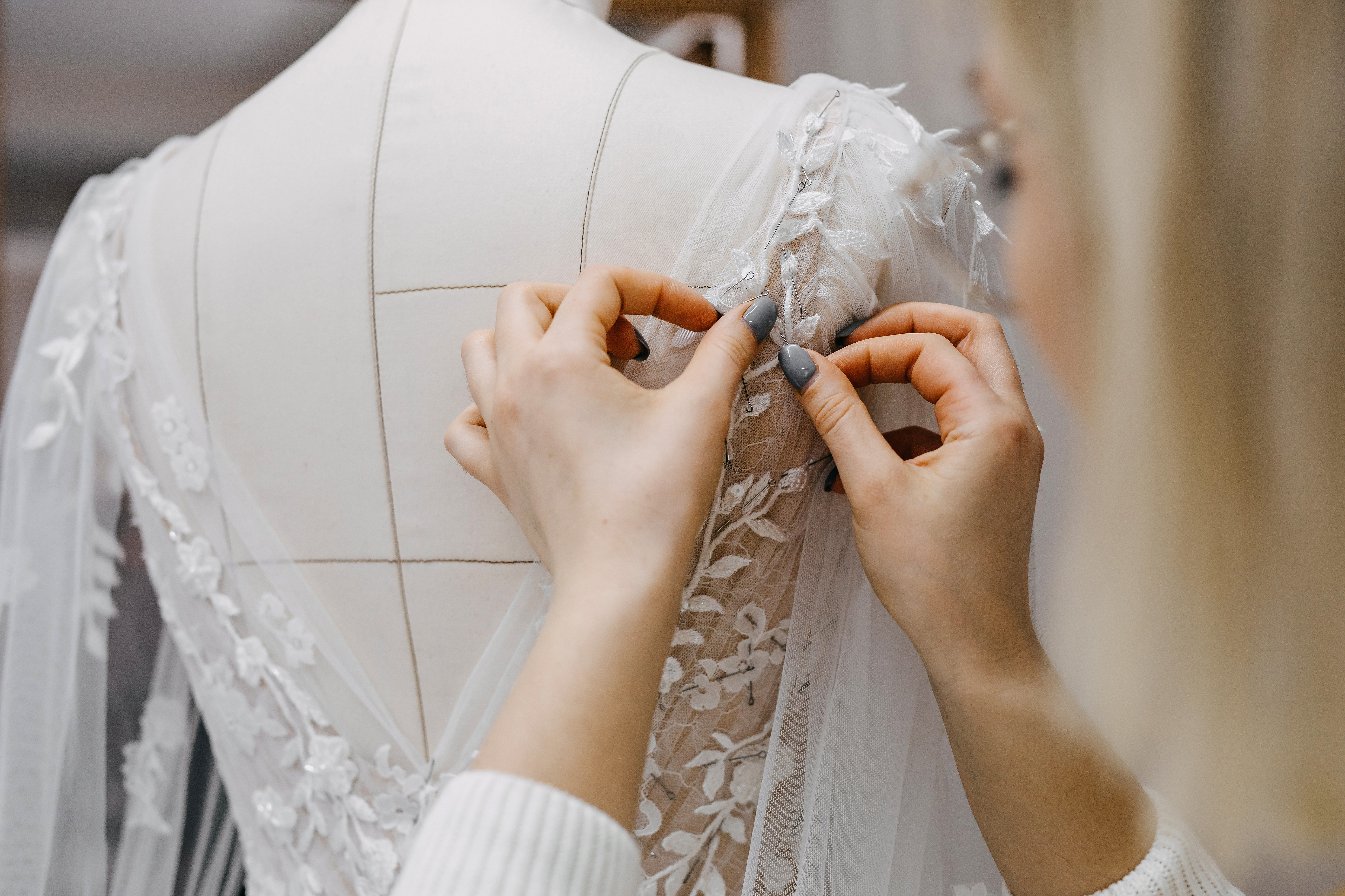 A woman sewing a bridal gown | Source: Shutterstock