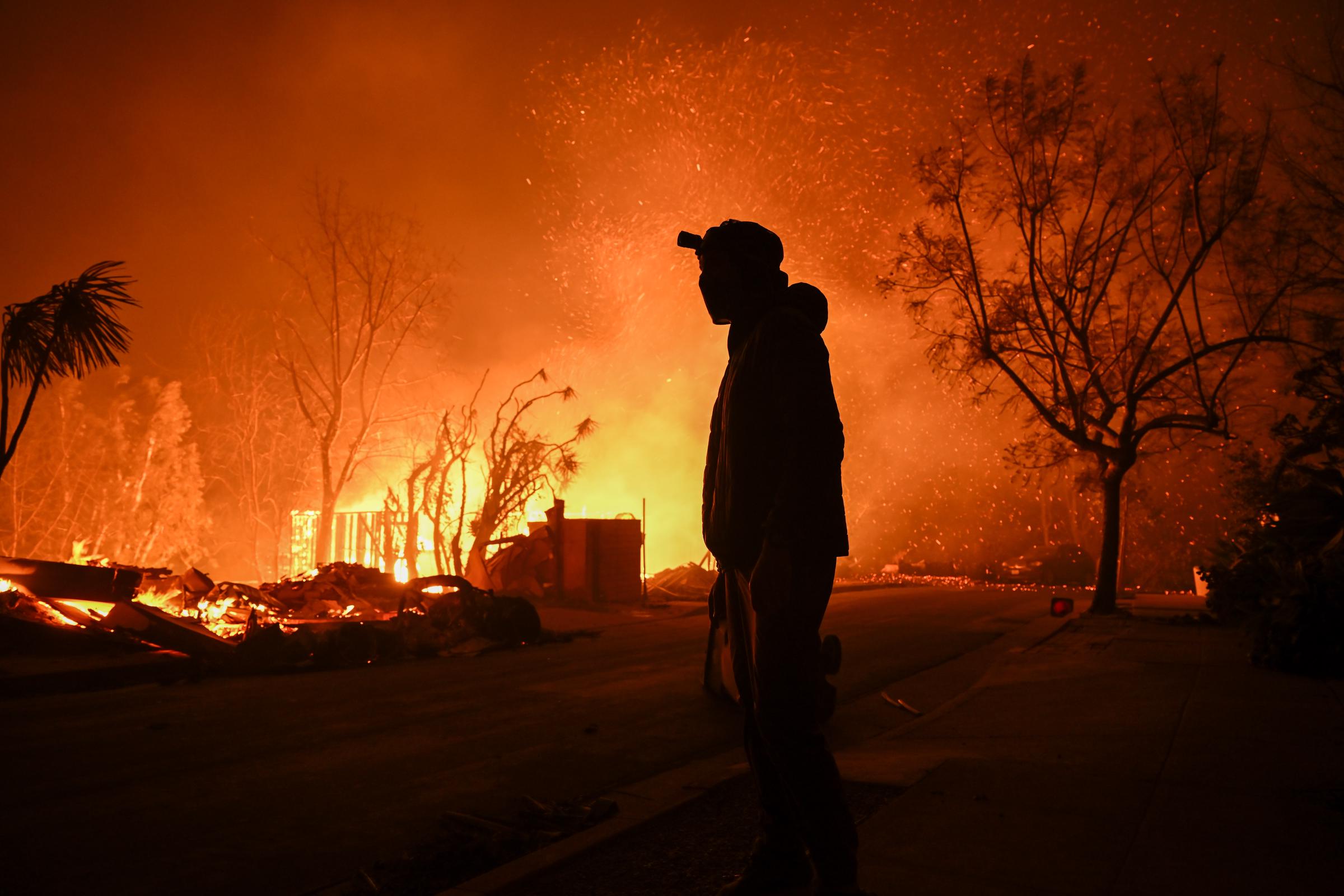 A civilian looking on as a home burns to the ground in Pacific Palisades, California on January 8, 2025. | Source: Getty Images