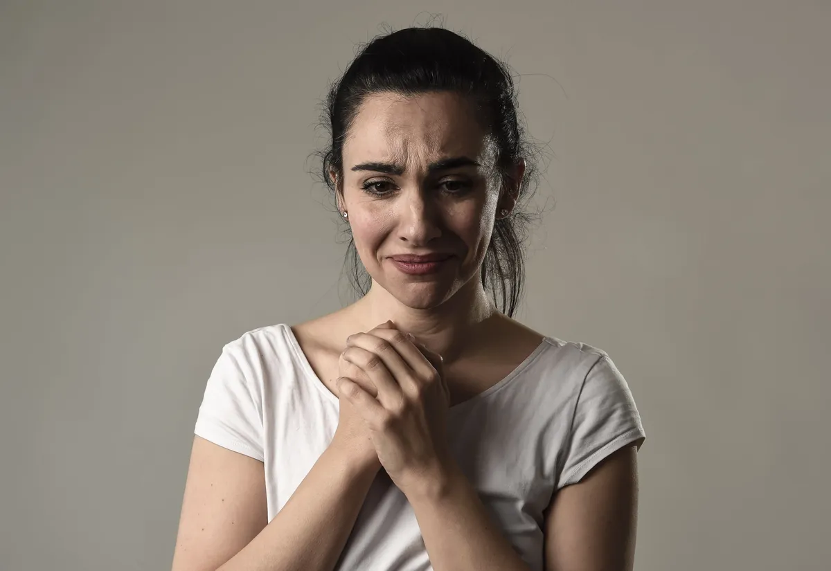 Eine Frau hält verzweifelt die Hände vor dem Körper zusammen. | Source: Shutterstock