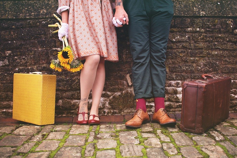 Pareja tomada de la mano posando con sus maletas. | Foto: Pixabay