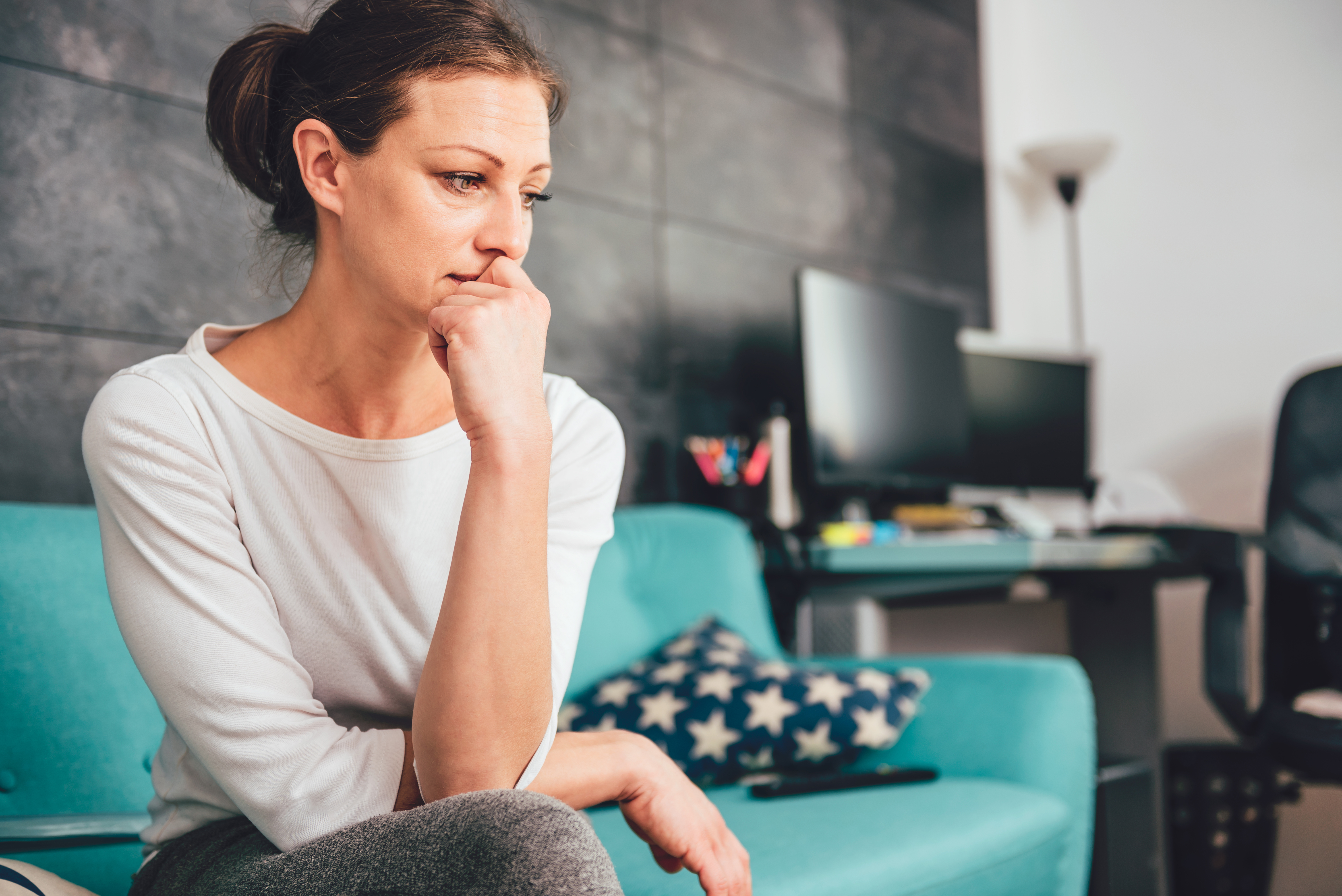 A sad woman sitting on a sofa | Source: Shutterstock