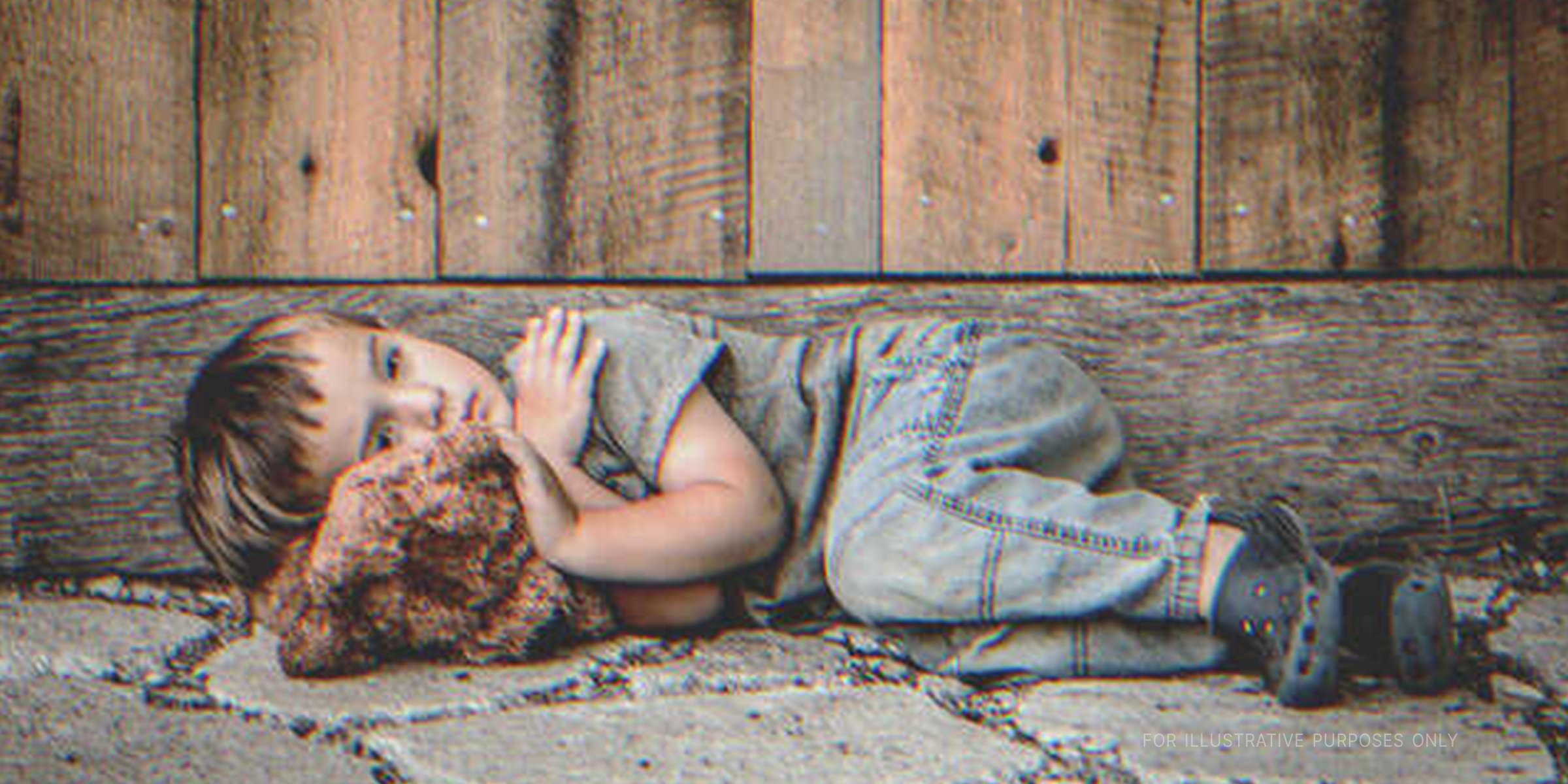Niño acostado en la calle con su osito | Foto: Shutterstock 
