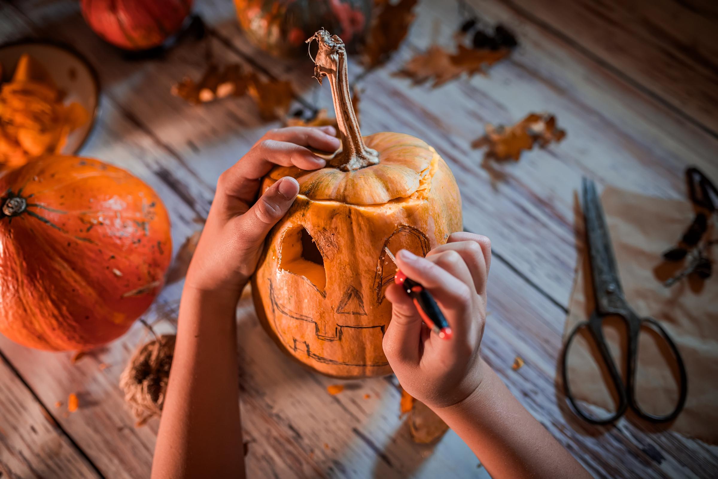 A young boy carving a face into a jack-o'-lantern | Source: Getty Images