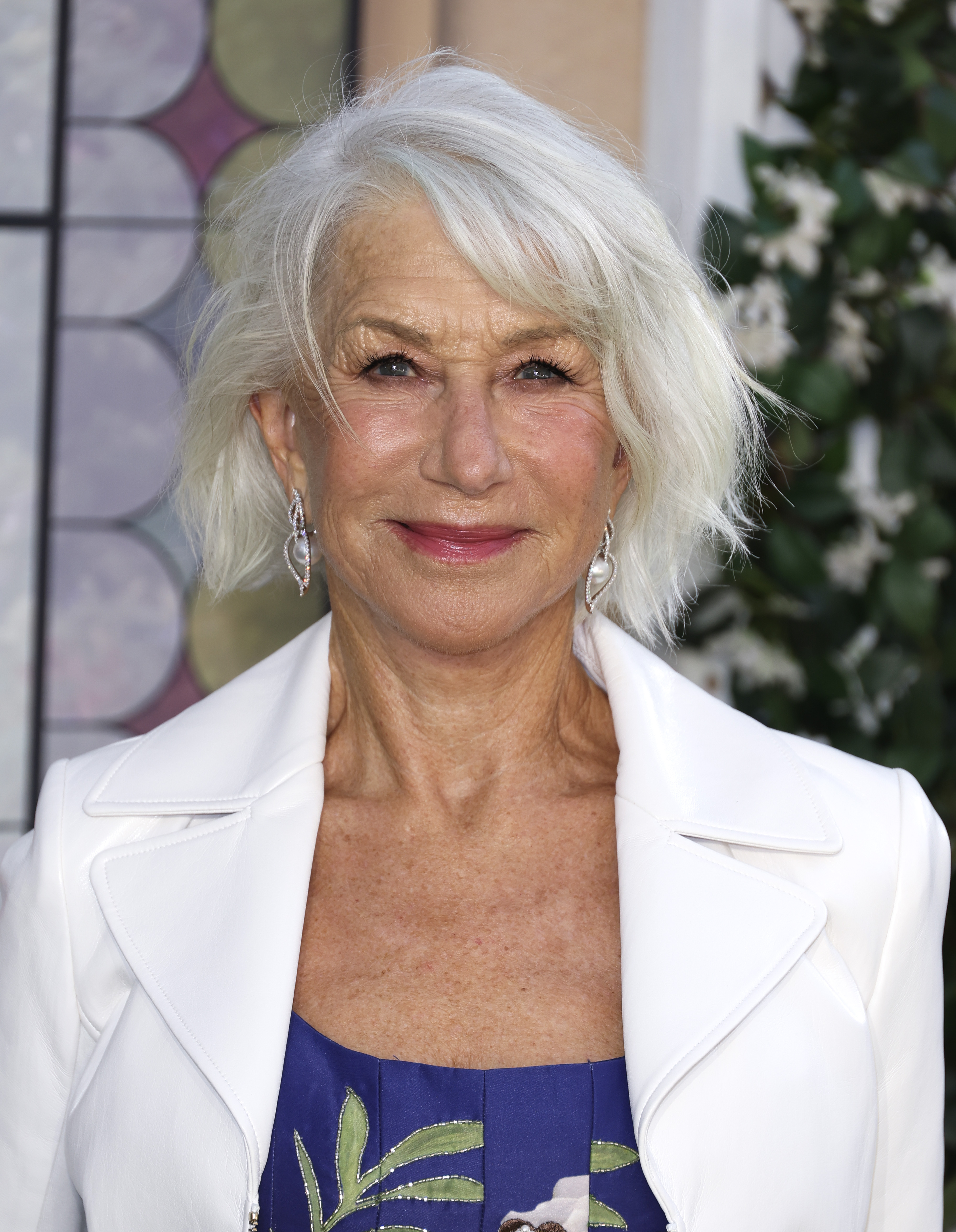 Mirren, now 80, brought effortless sophistication to the London premiere of "The Thursday Murder Club" in a structured white jacket over a floral-accented blue dress. Her windswept silver bob, statement earrings, and rosy lip gave her a fresh, confident glow — classic, unfussy, and wholly in command of her presence.
