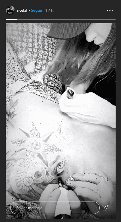 Christian Nodal en el momento exacto que le tatúan los ojos de Belinda. | Foto: Captura de historia de Instagram / Nodal