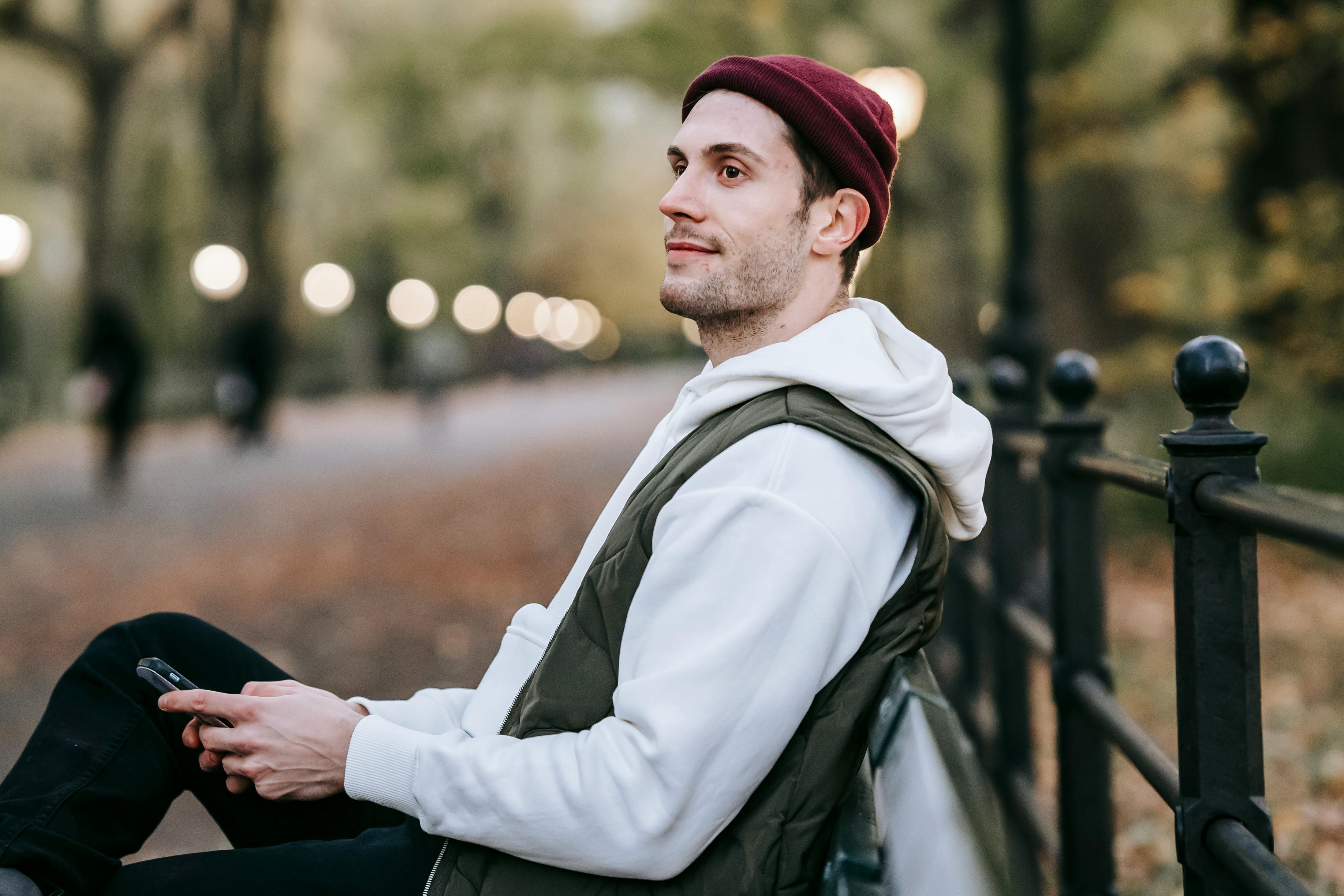 A happy man hanging out at a park with his phone in his hand | Source: Pexels