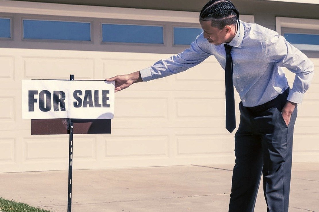 Un hombre termina de colocar un anuncio de venta en una propiedad. | Foto: Pexels