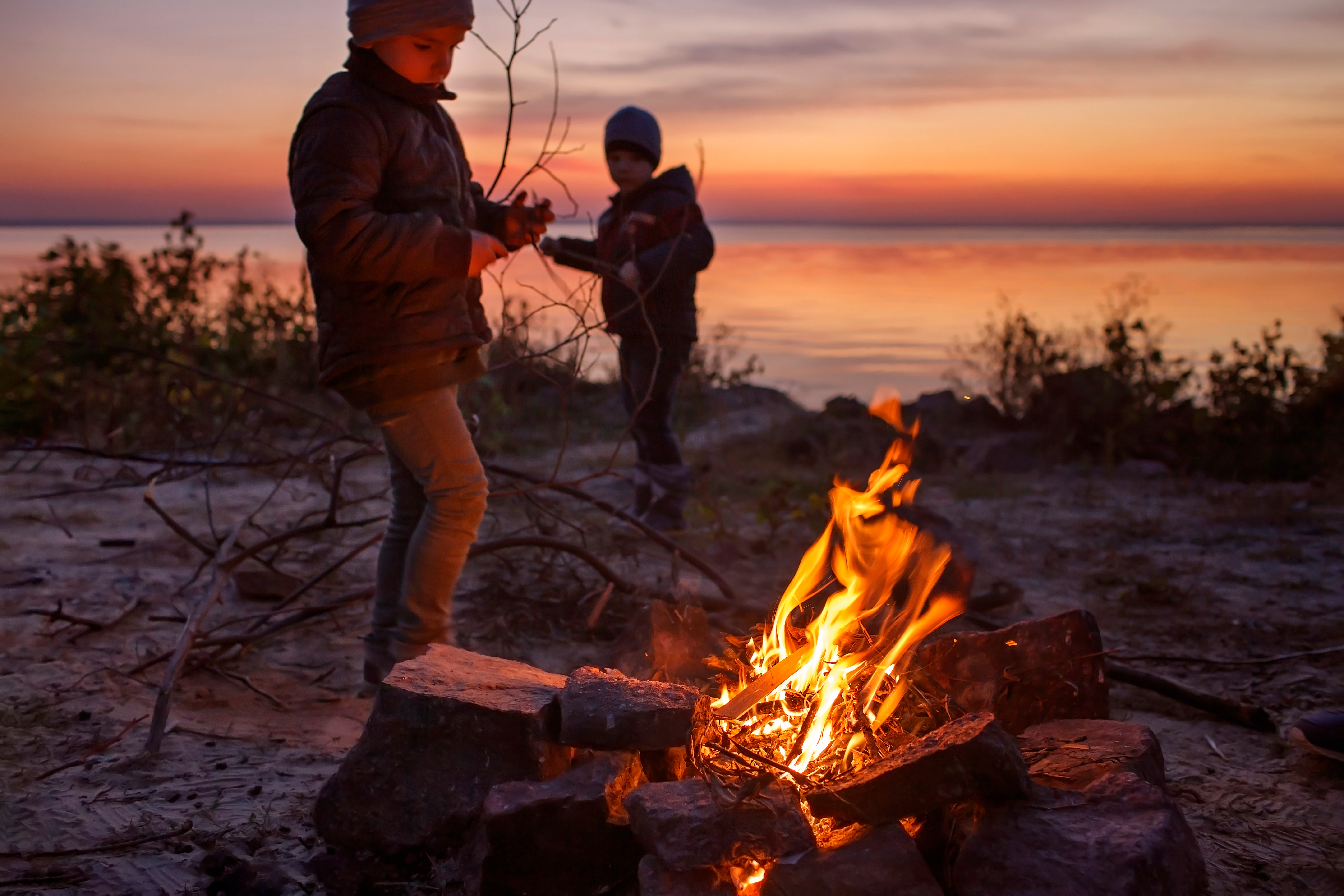 Kids of different ages sit near fire | Source: Shutterstock.com