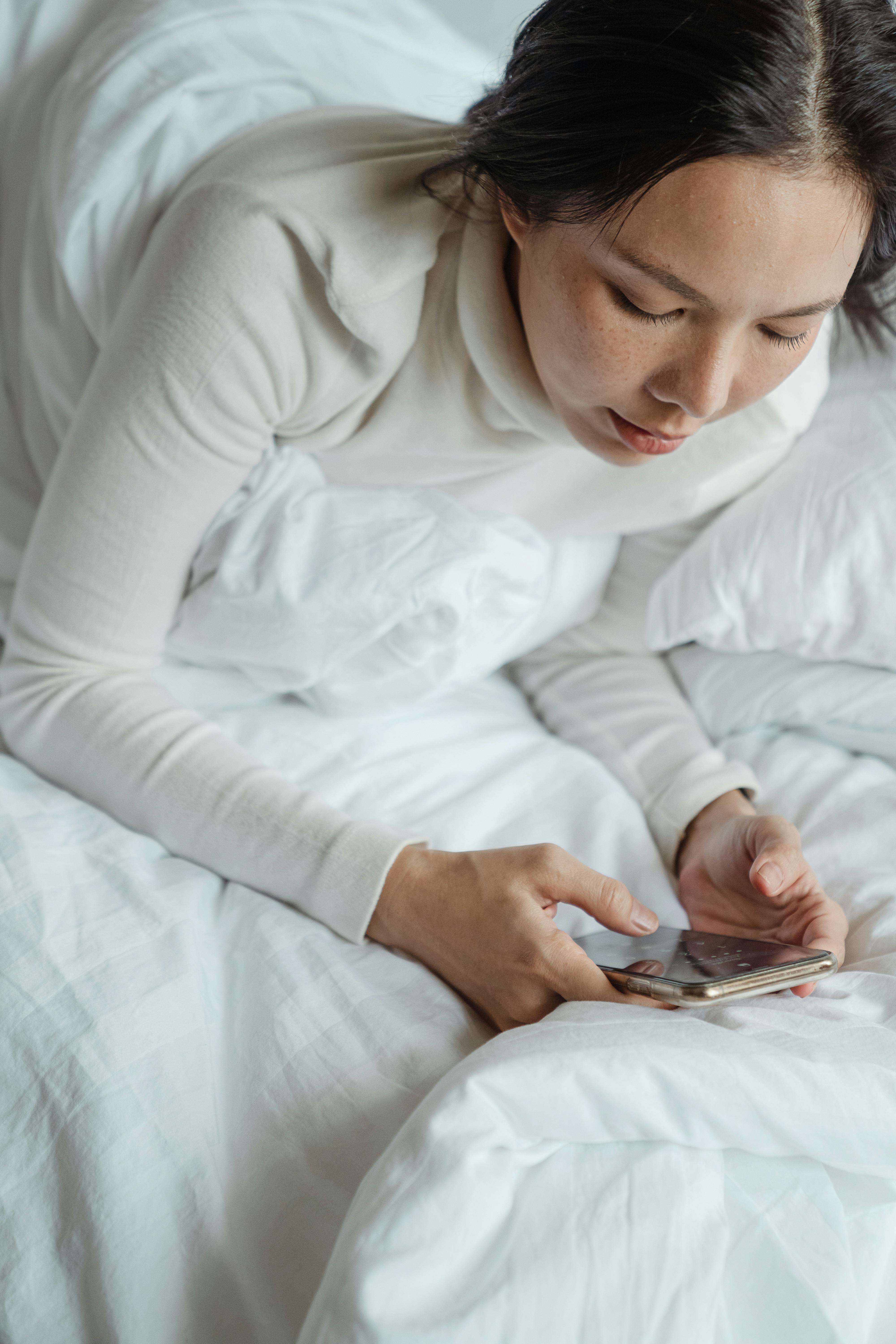 A woman using her phone in bed. | Source: Pexels