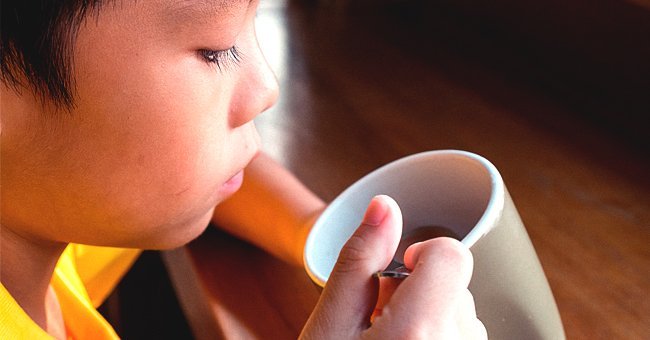 A young boy sipping from a cup of coffee | Photo: Shutterstock