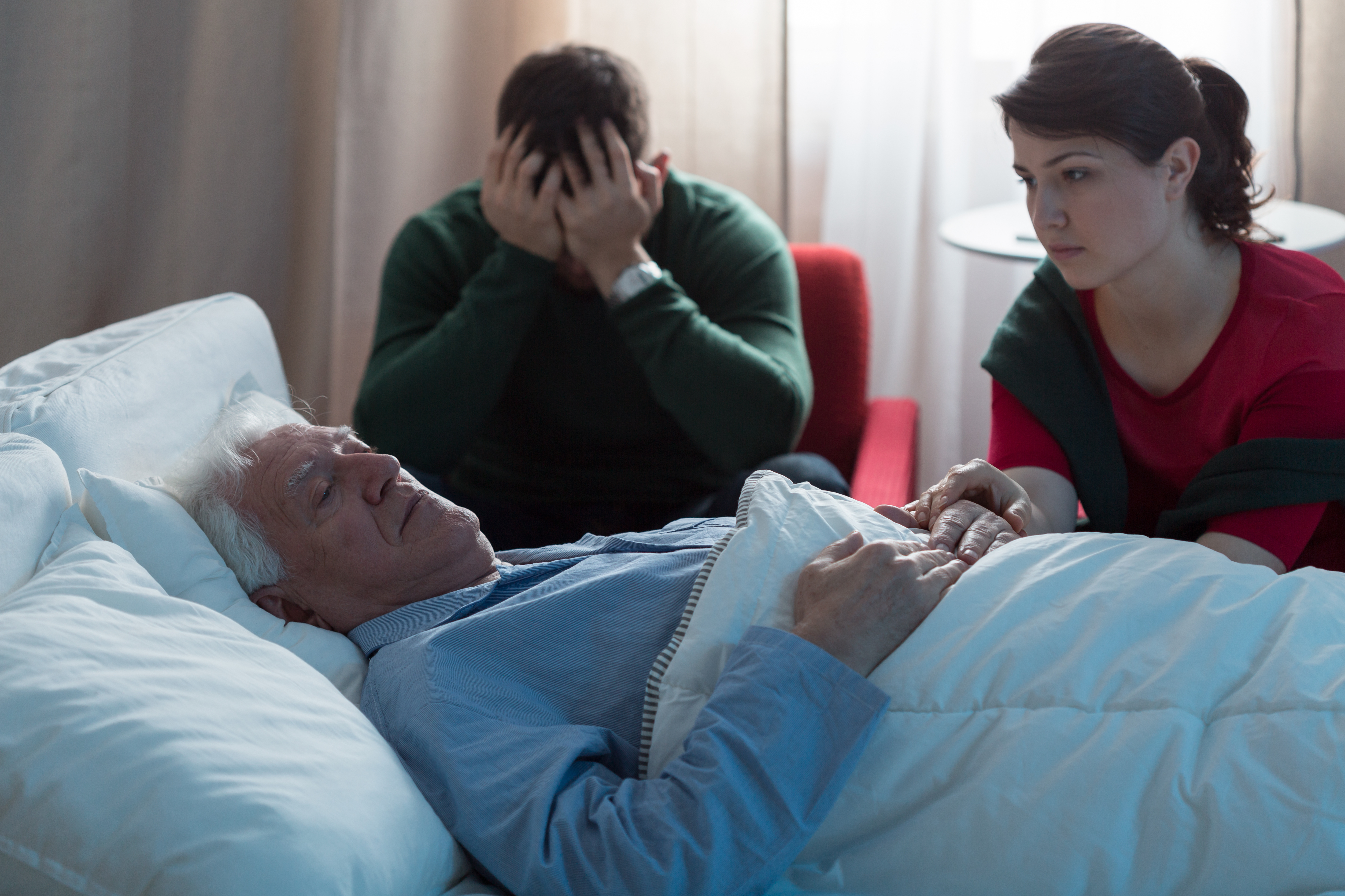 Ein alter Mann im Krankenhaus, umgeben von seiner Familie | Quelle: Shutterstock