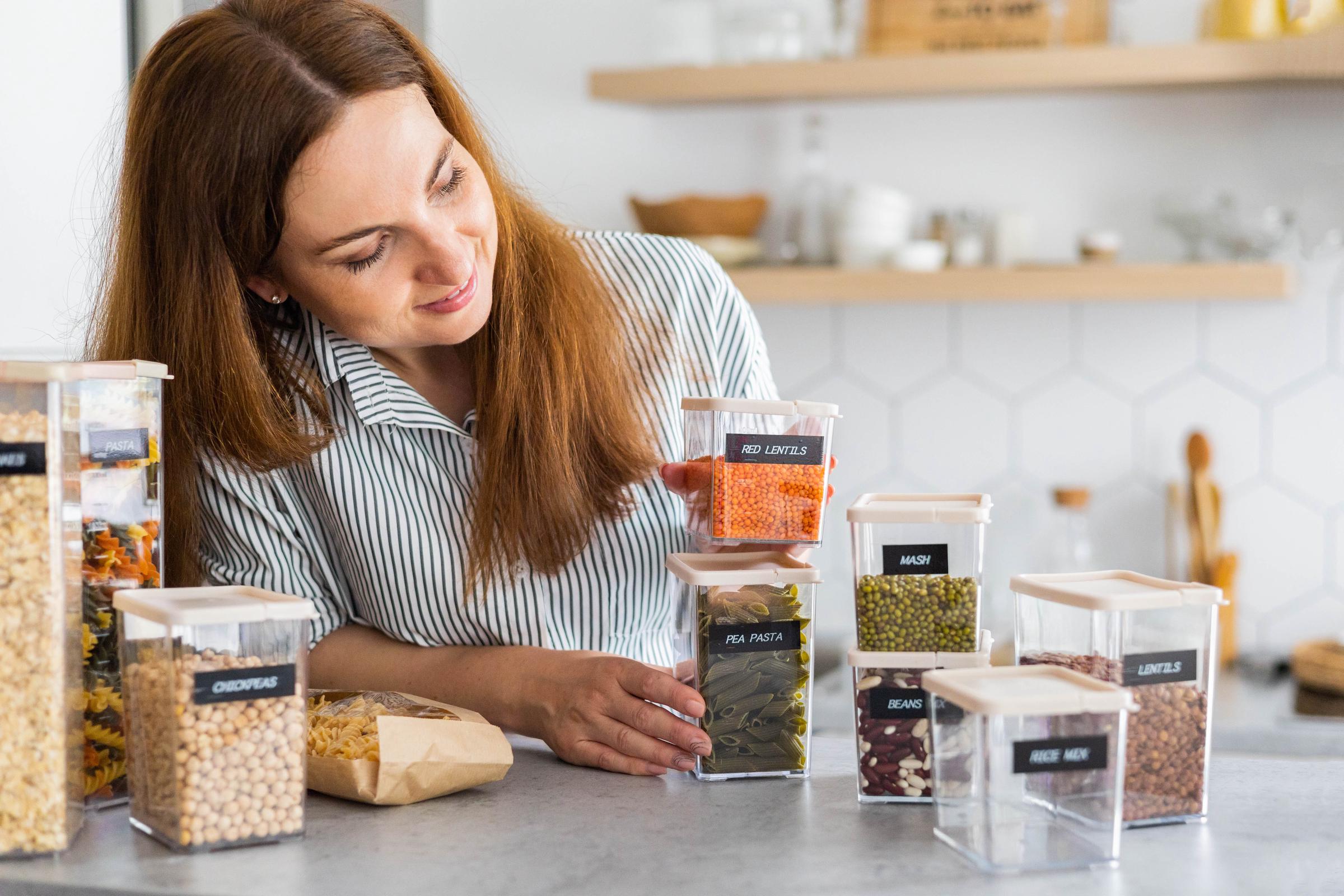 Woman storing food in labeled bins | Source: Shutterstock