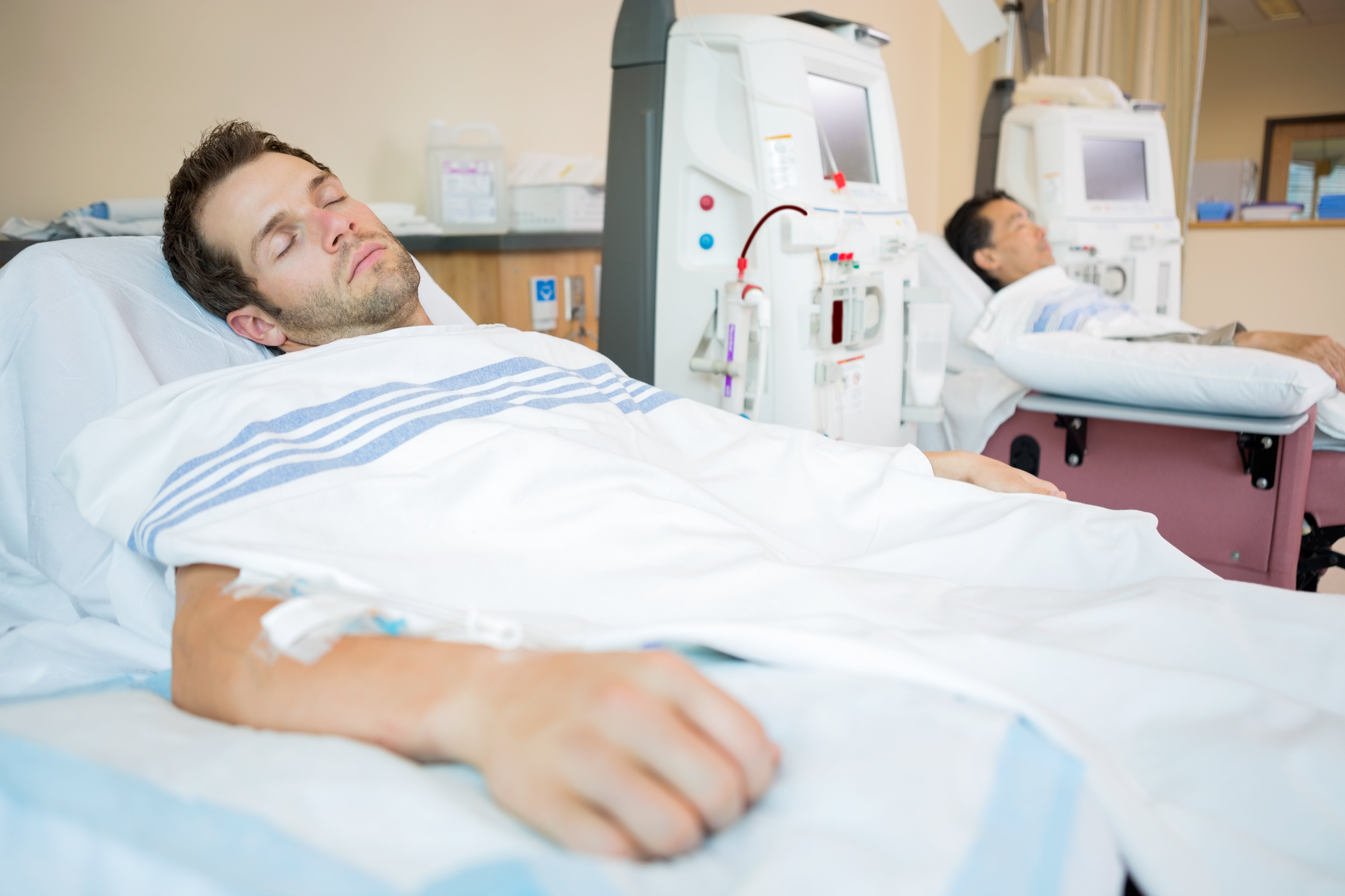 Male patients sleeping while receiving renal dialysis in chemo room at hospital | Photo: Shutterstock.com