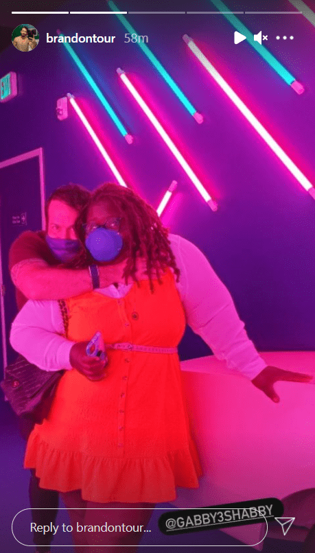 Brandon Frankel hugs Gabby Sidibe inside a dim room with neon lights. | Photo: instagram.com/brandontour