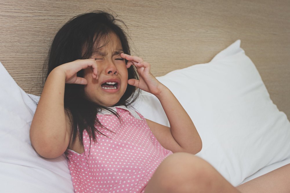 Niña llorando en la cama. | Fuente: Shutterstock