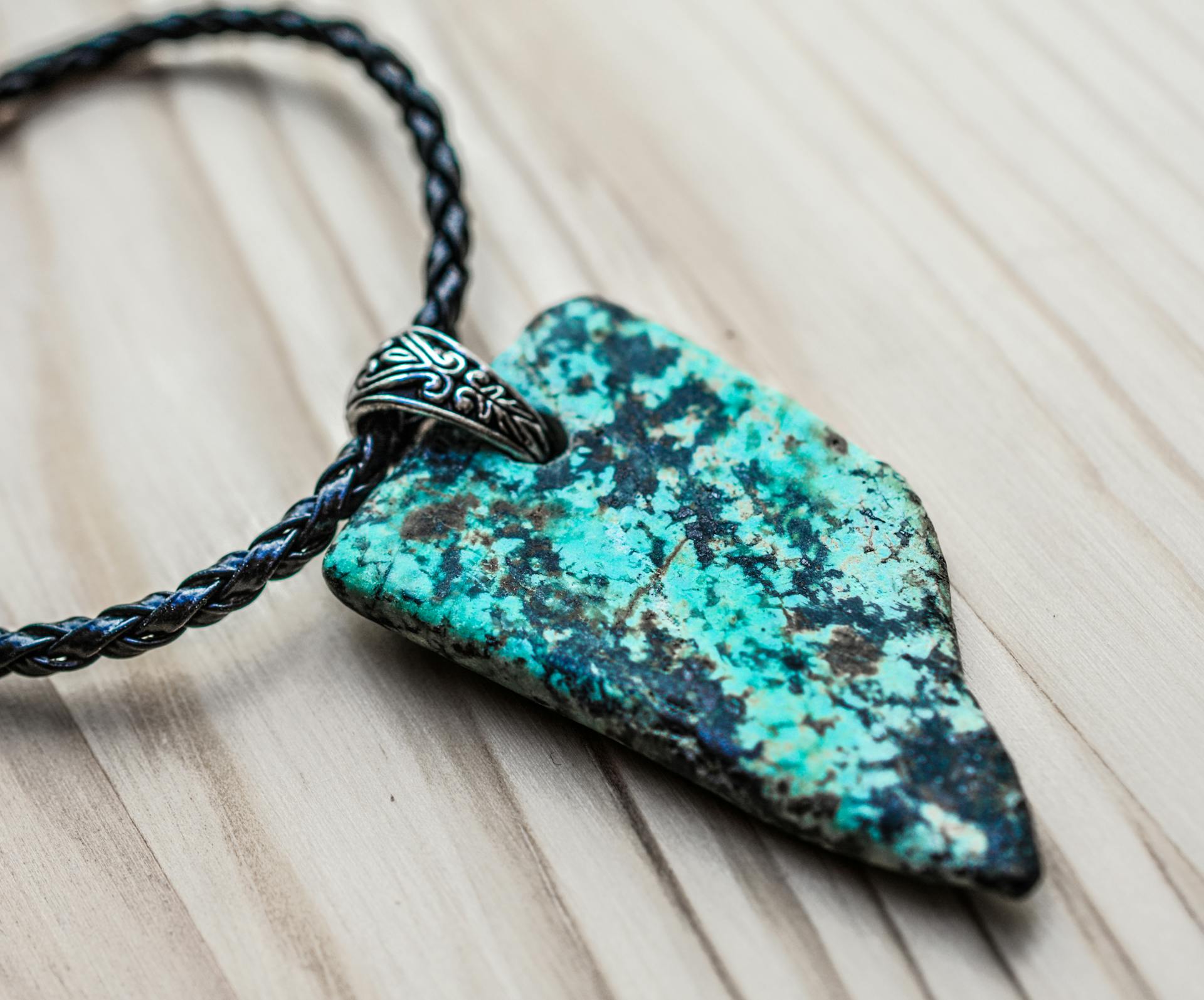 A gray and black stone pendant on a black necklace | Source: Pexels