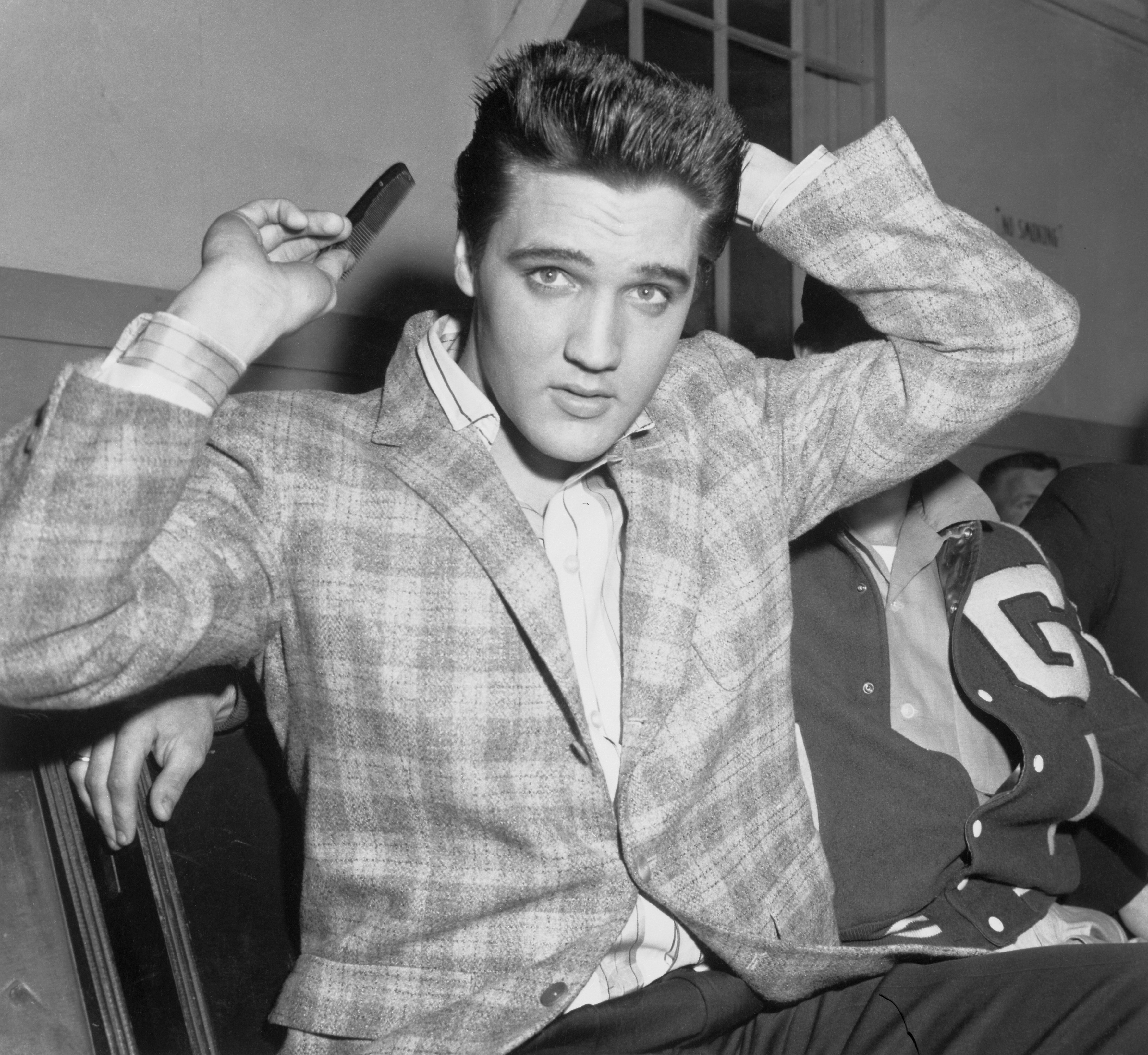 Elvis Presley runs a comb through his famous tresses at the Draftee Receiving Depot here on March 24th | Source: Getty Images 