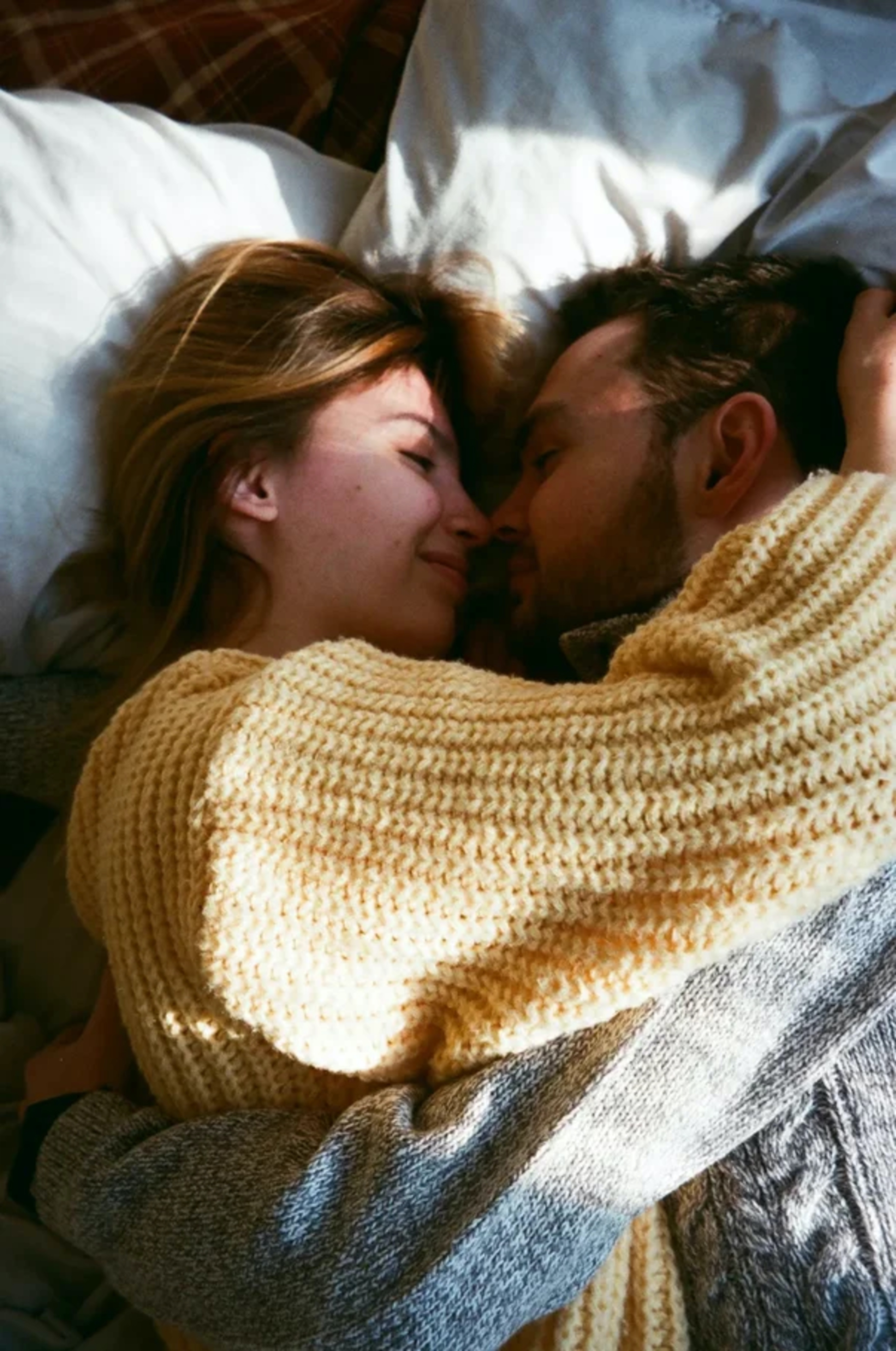 Woman in knit sweater lying in a bed with a man. | Source: Pexels