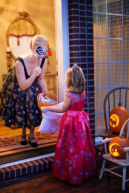 Young girl is trick-or-treating with woman who has face masks and treats | Photo: Pixabay