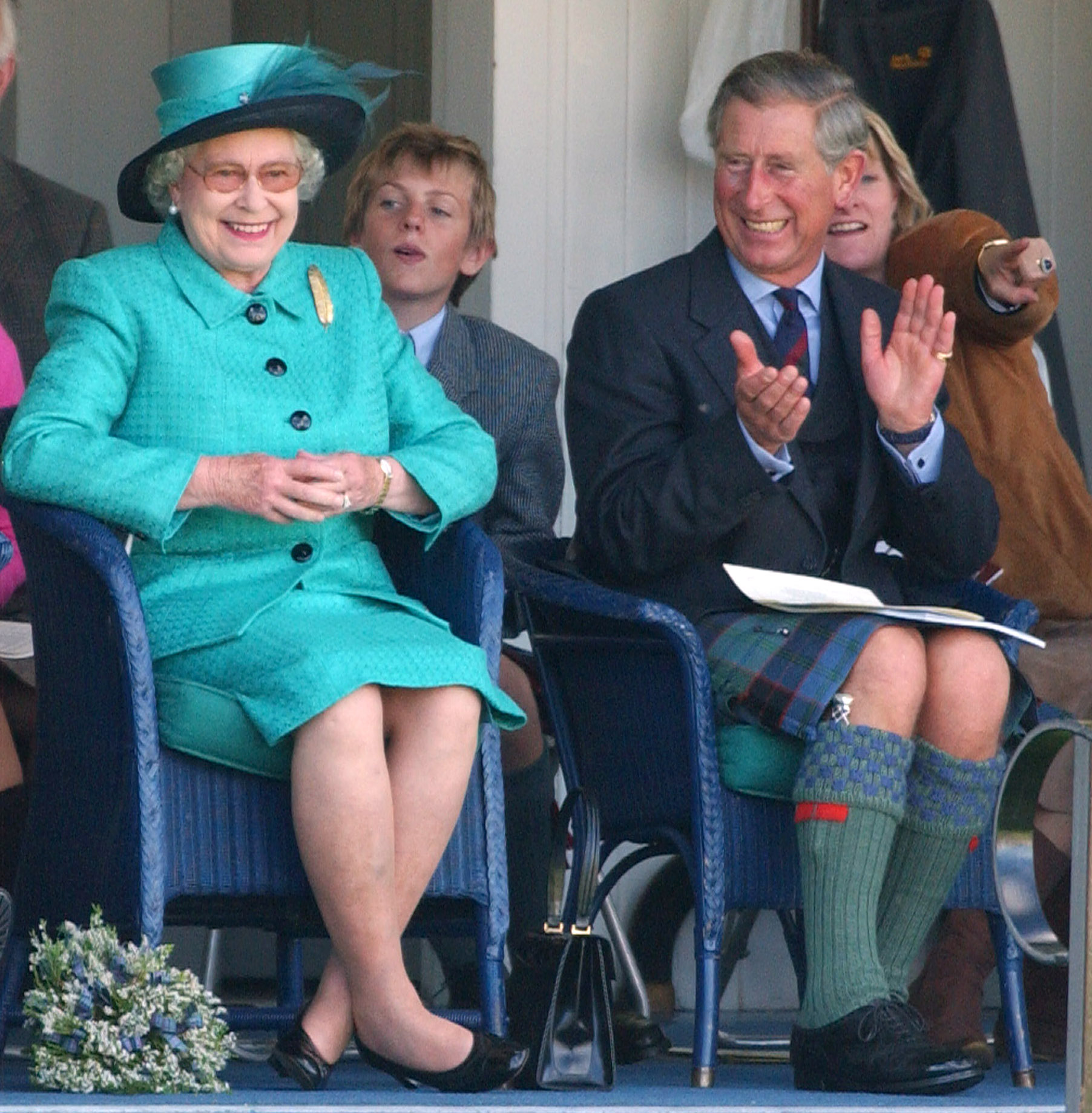 At the Braemar Highland Games in Scotland in 2004, Queen Elizabeth II is seen seated alongside Prince Charles, Prince of Wales, both smiling as they watch the festivities unfold, the relaxed setting and traditional attire offering a glimpse into the royal family's long-standing connection to Scottish heritage and public life.