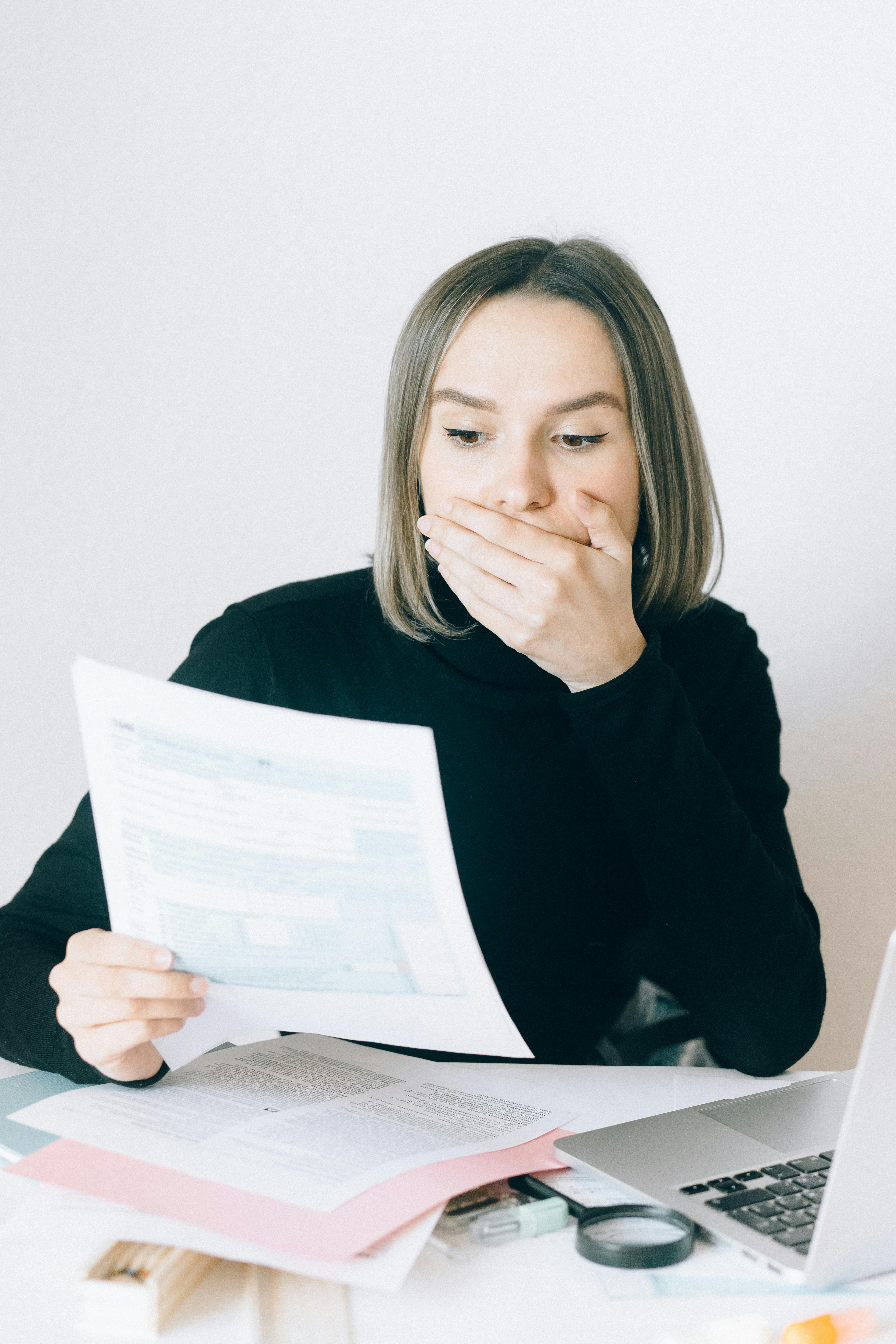 A shocked woman holding a document | Source: Pexels