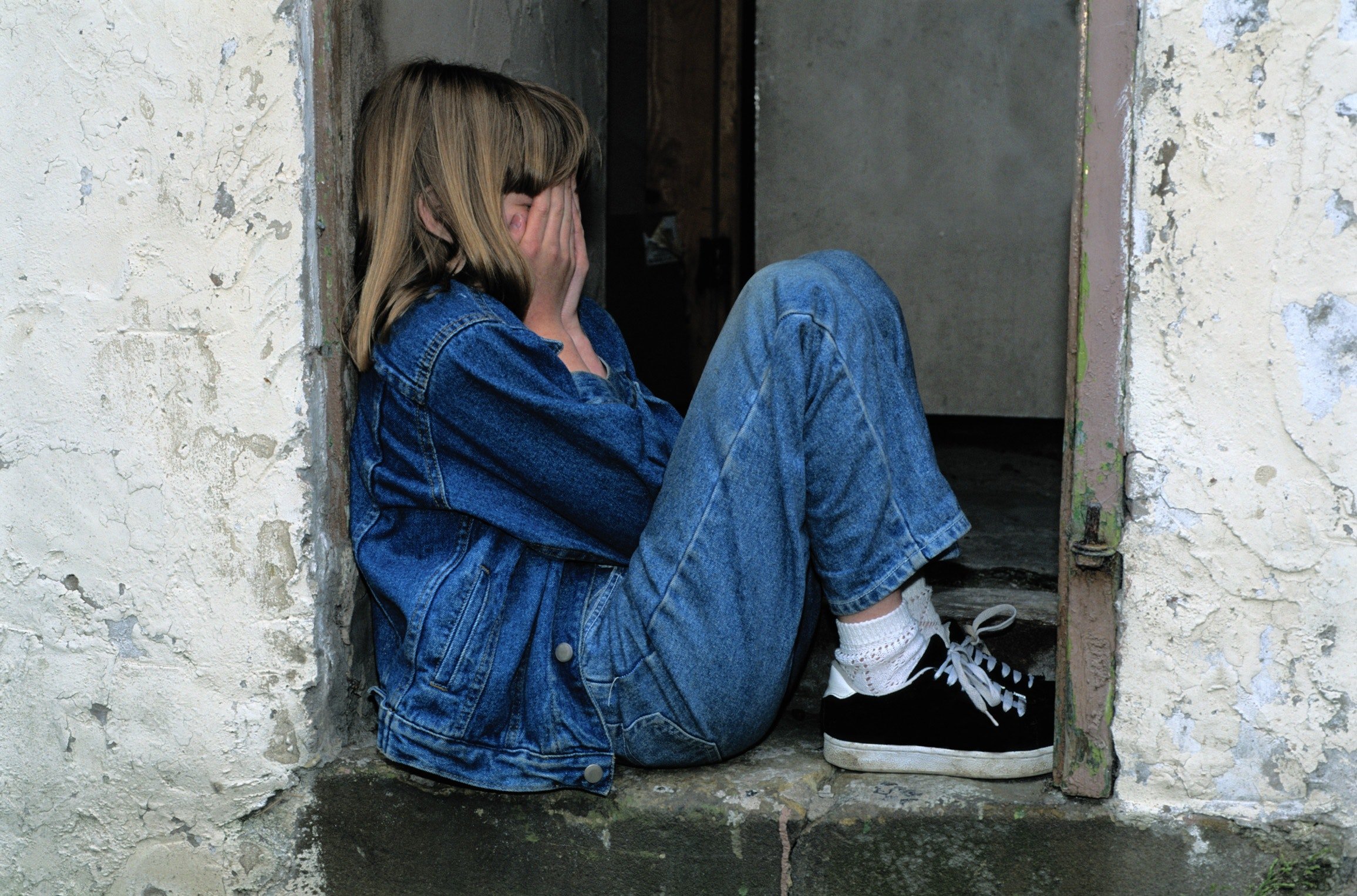 Niña pequeña llora sentada en la entrada de su hogar. | Foto: Pexels