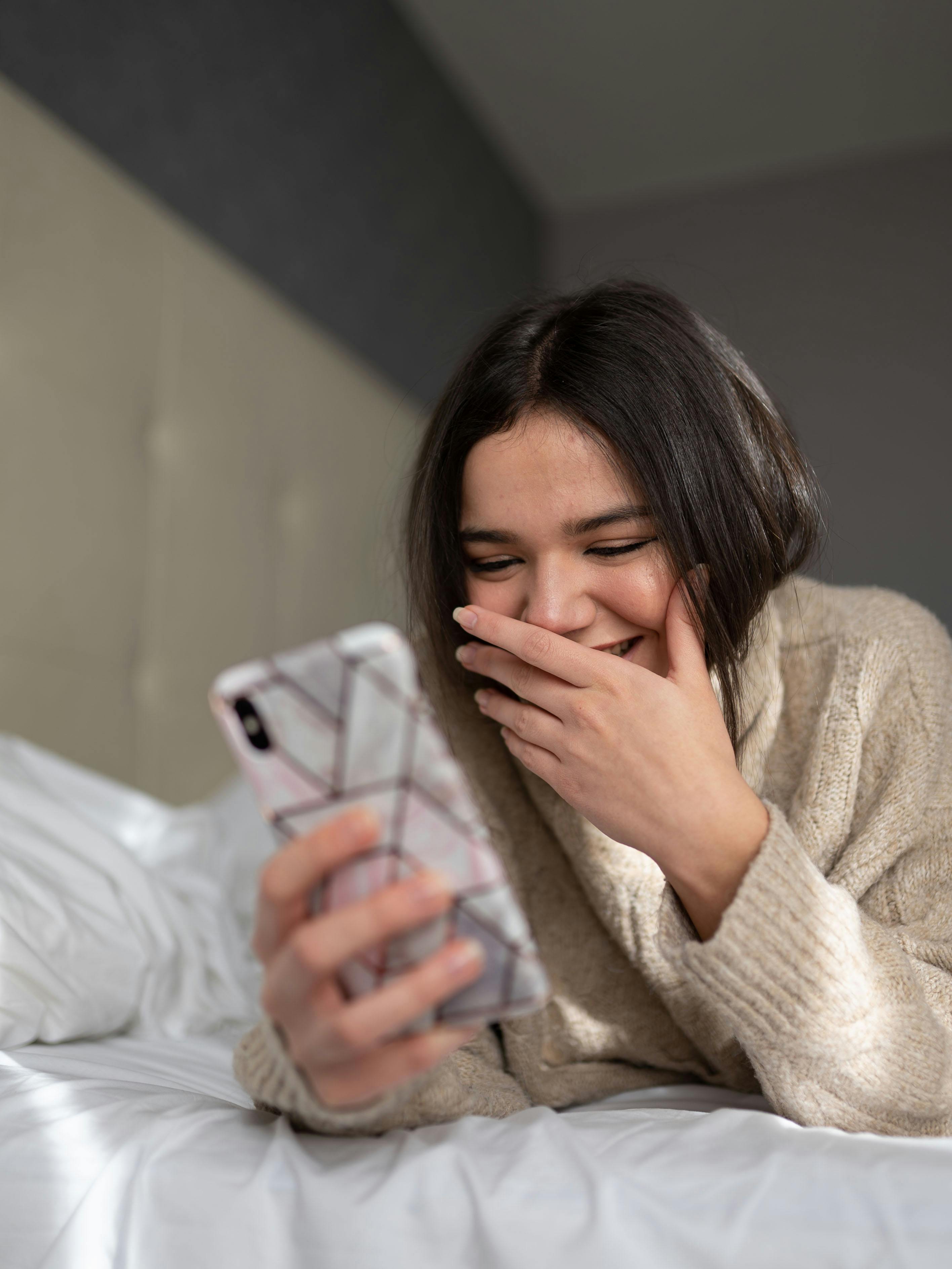 A happy woman using her phone | Source: Pexels