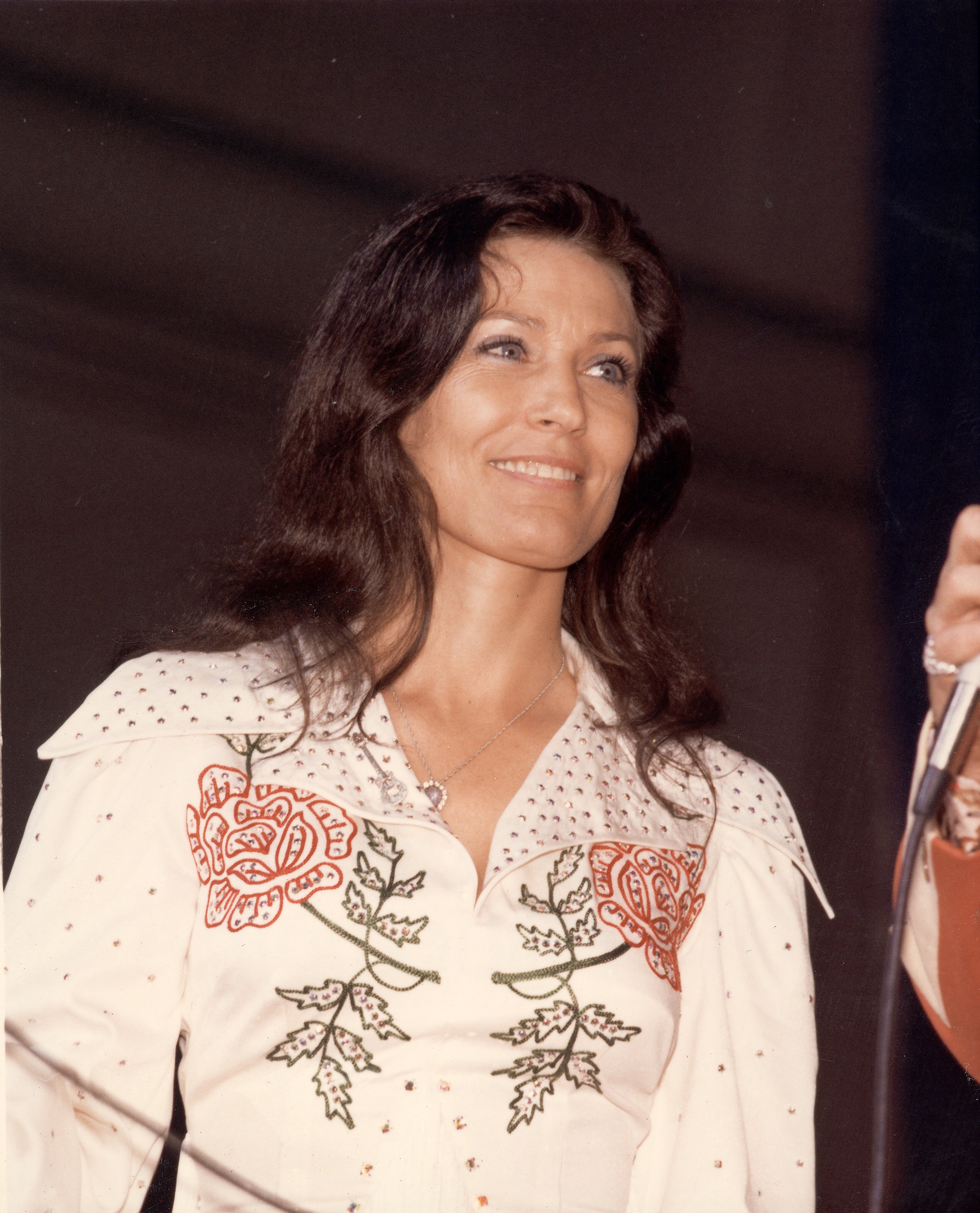 American country music singer and guitarist Loretta Lynn smiles as she looks at an unidentified person off-camera who holds a microphone the late 1970s. | Source: Getty Images