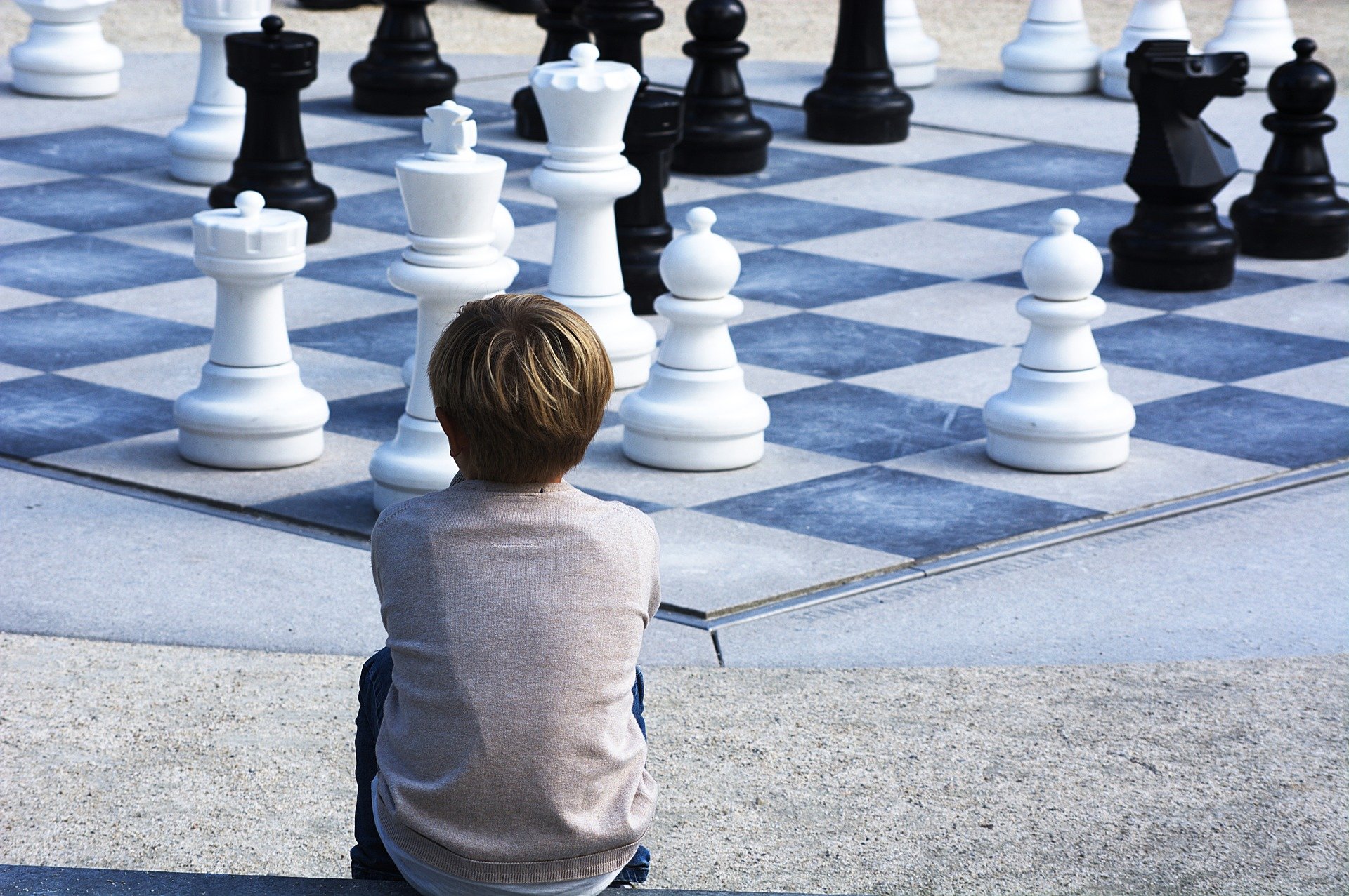 Pictured - A young boy sits and looks over at a chess landscape | Source: Pixabay 