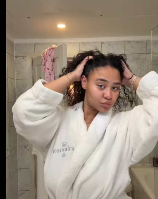 Brianna McKnight lifts both hands to her hair, pushing it back from her face while looking toward the mirror, from a post dated December 4, 2025. | Source: TikTok/brimcknighttt