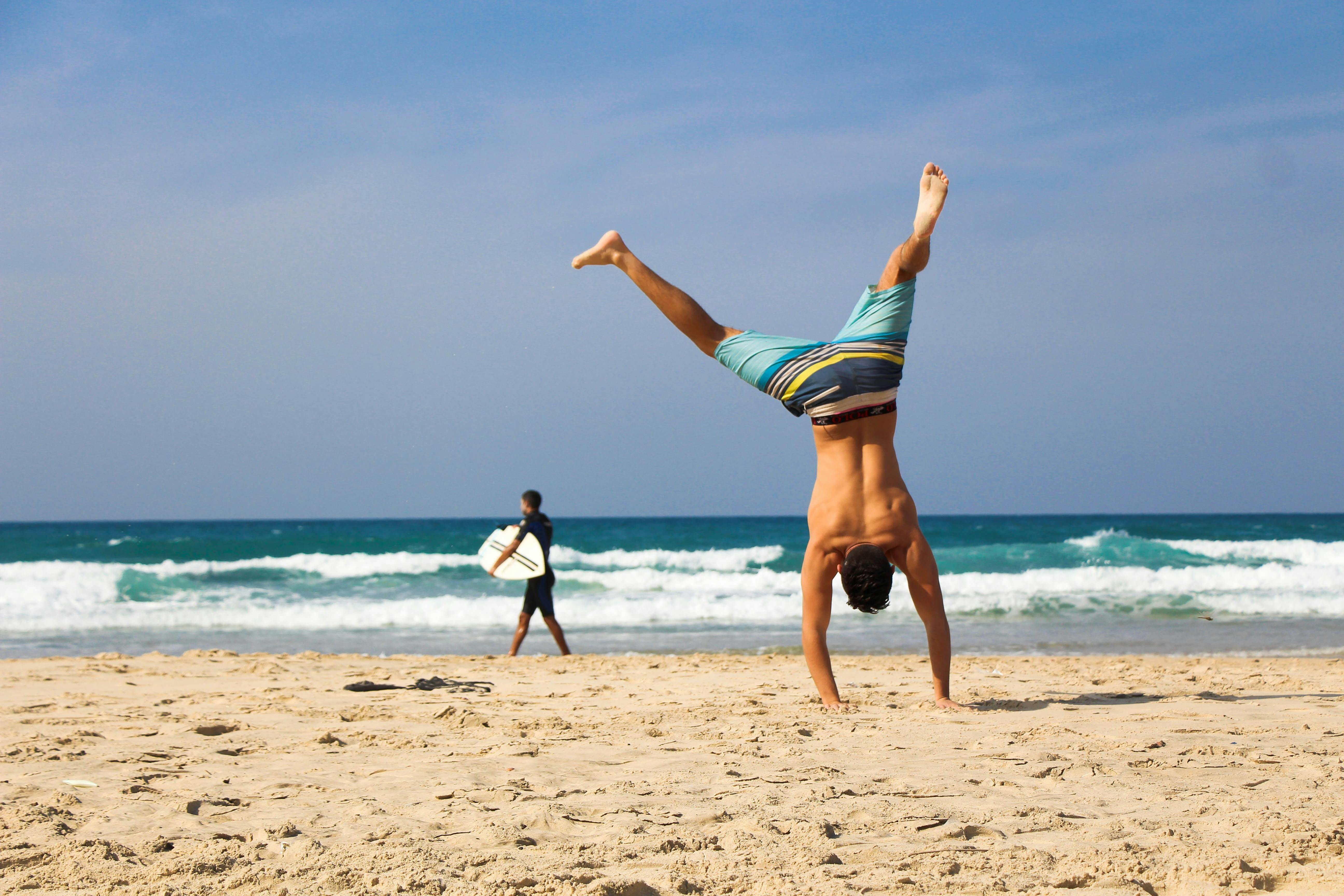 Man does a handstand on a beach | Source: Pexels