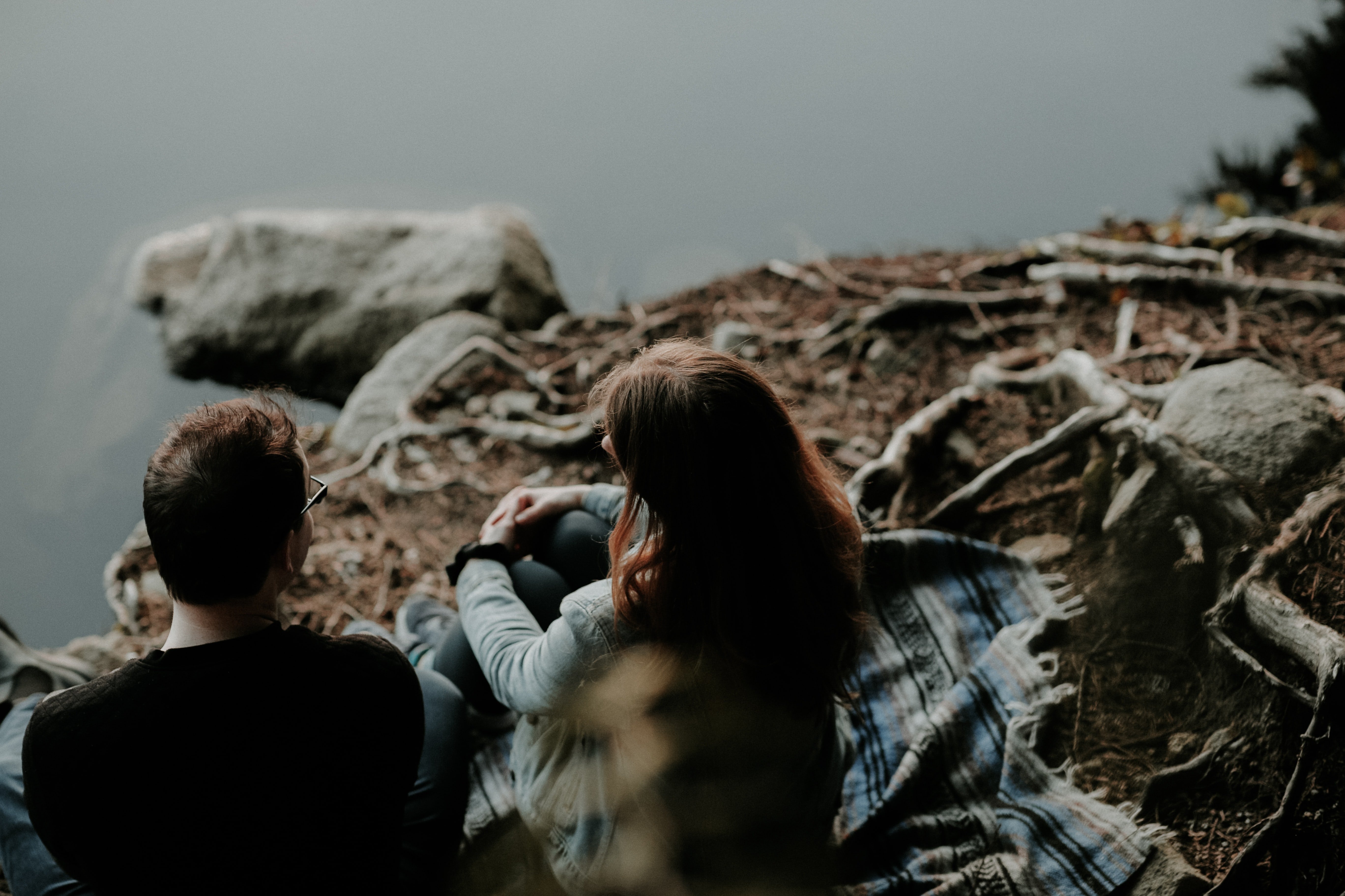Un hombre y una mujer conversan sentados a orillas de un rio. | Foto: Pexels